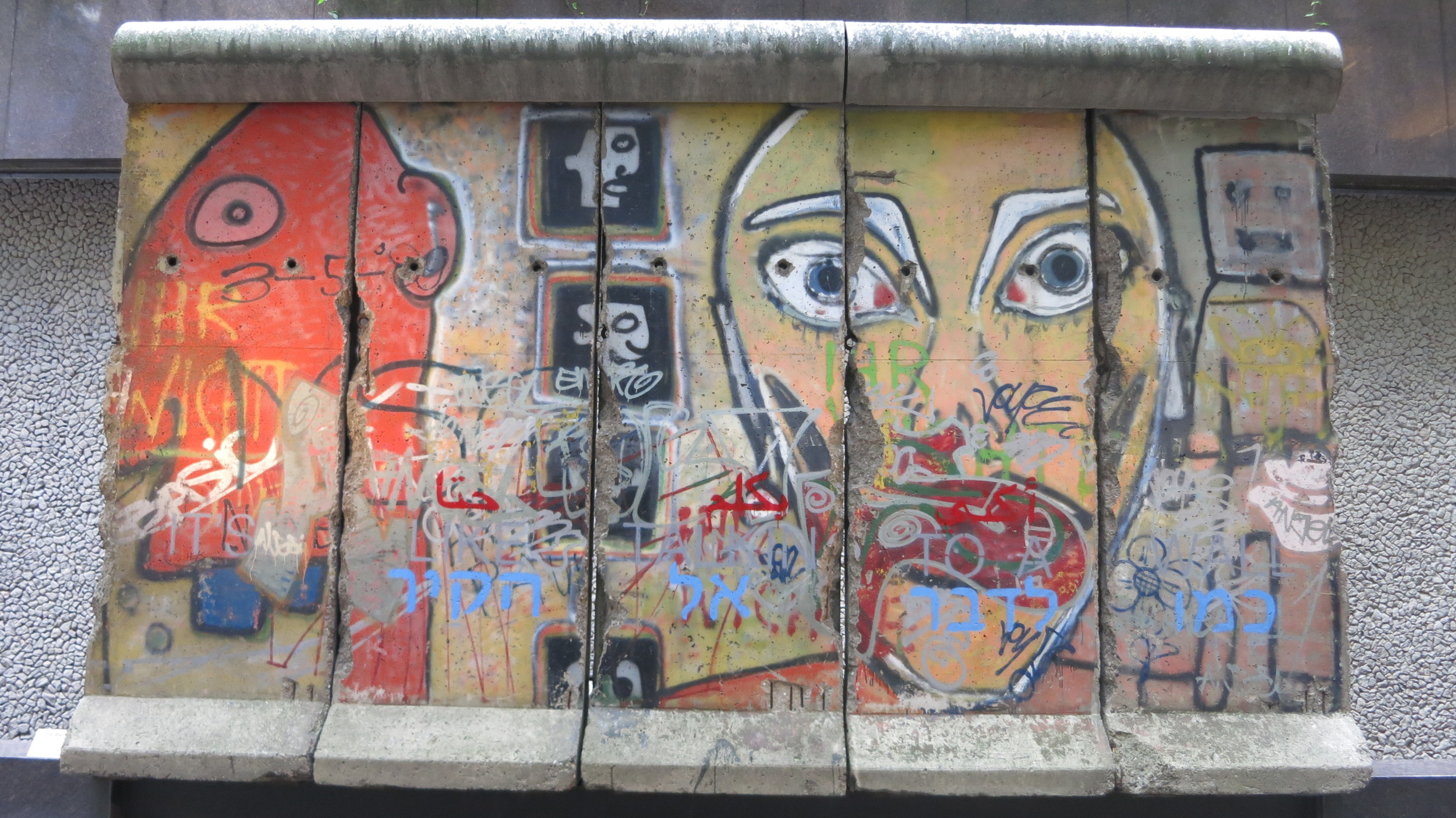  The mural after the 2014 graffiti vandalism. The words “IT’S LIKE TALKIN TO A WALL” were spray painted across the surface in three different languages and colors: Arabic in red, English in gray, and Hebrew in blue.&nbsp;  
  
 
  
    
  
 Normal 
 