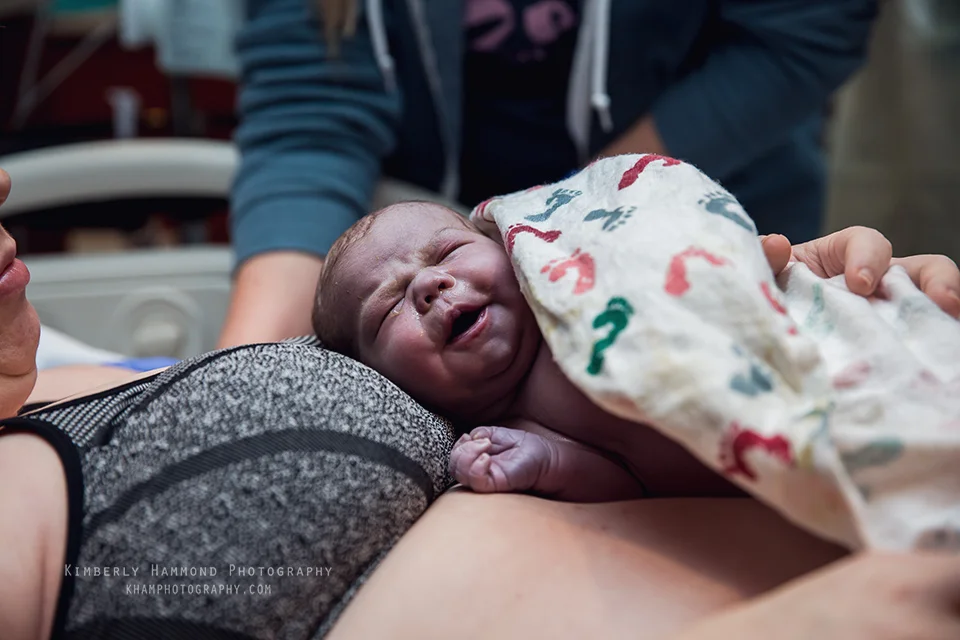 Newborn baby grins during natural hospital birth in Grapevine TX.