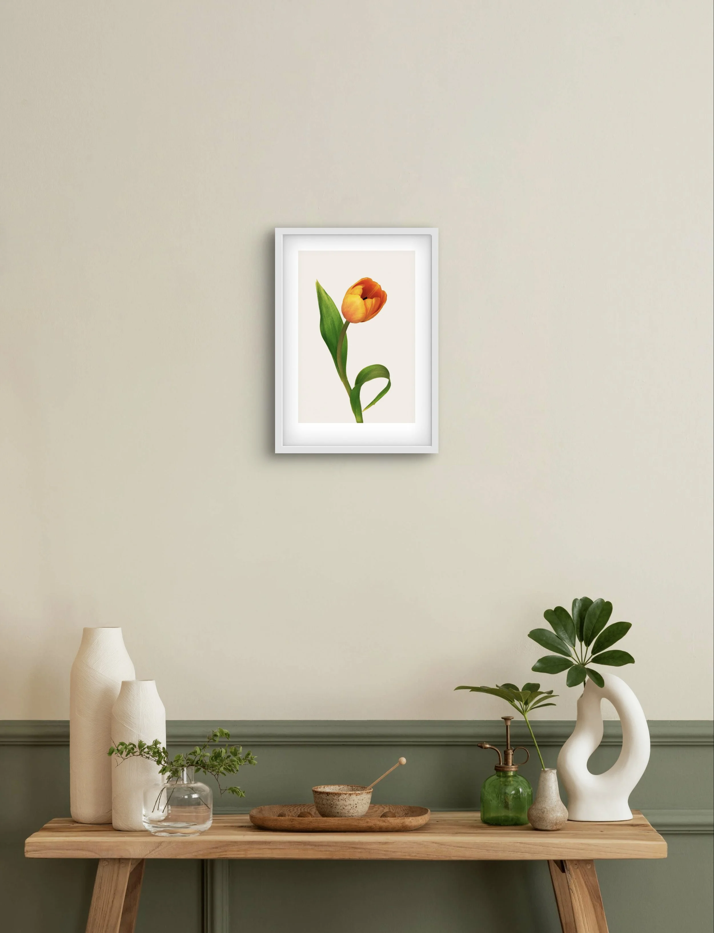 Framed tulip print with warm orange tones, shown in a softly lit interior. The flower’s tilted form adds a touch of movement to the calm, minimal room.