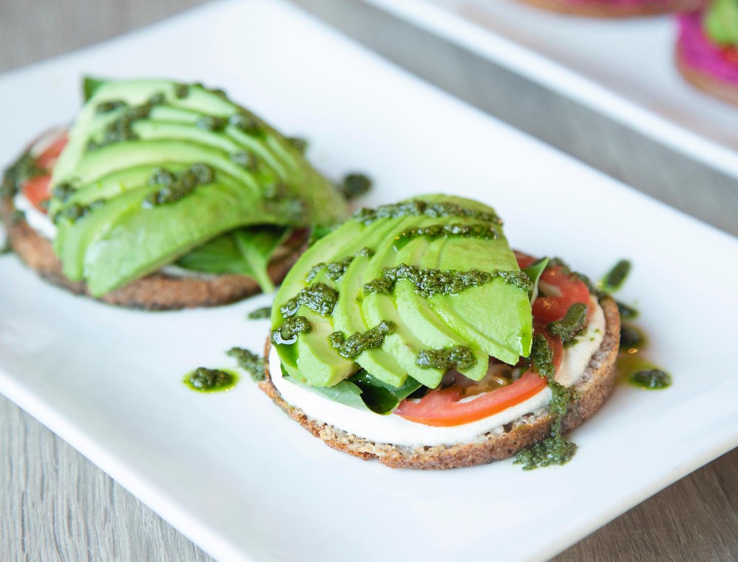 Introducing our Vegan Caprese Toast! 🌱🥑🍅 Savor the flavors of summer with our gluten-free, grain-free @livepacha bun topped with creamy cashew cheese, ripe tomato, fragrant basil, and creamy avocado. Finished off with a drizzle of pesto, it&rsquo;