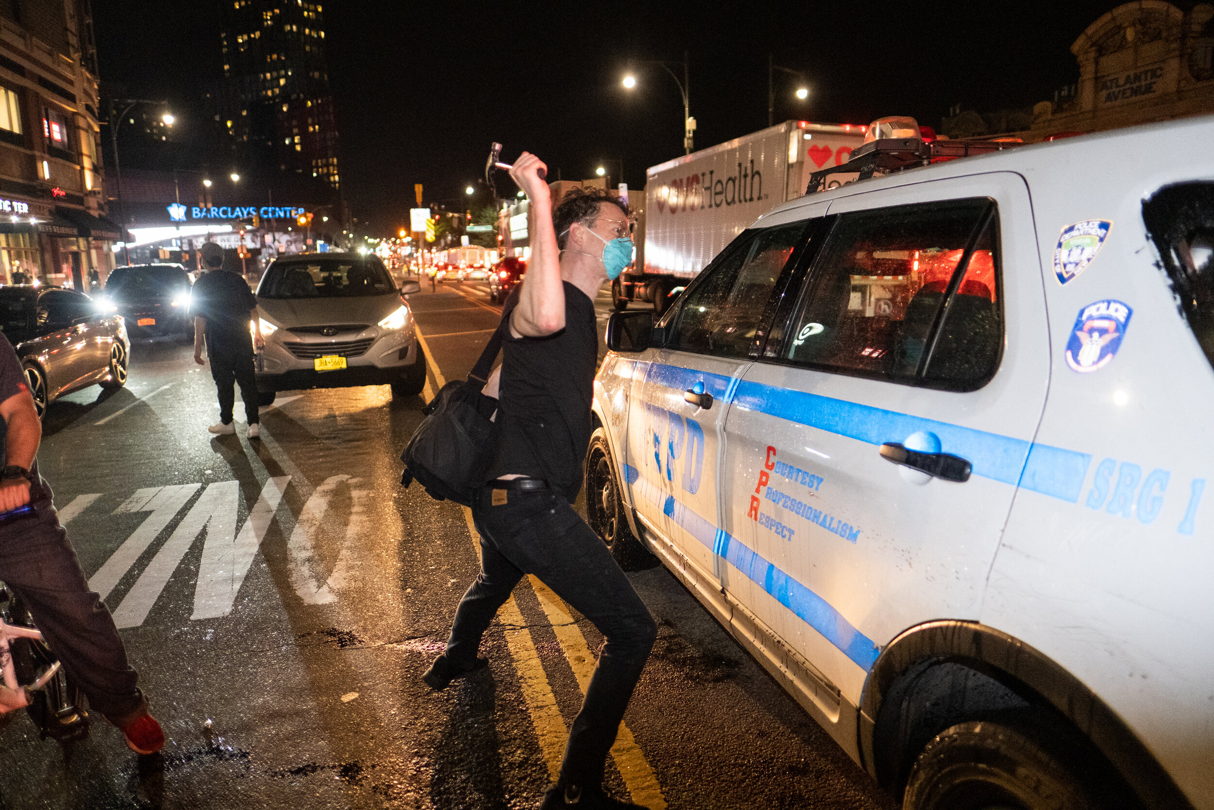  May 29, 2020: New York, NY -   A man smashes the window of a NYPD vehicle as protesters clash with NYPD officers near the Barclay’s Center after George Floyd was killed while being detained by Minneapolis police on May 25.  