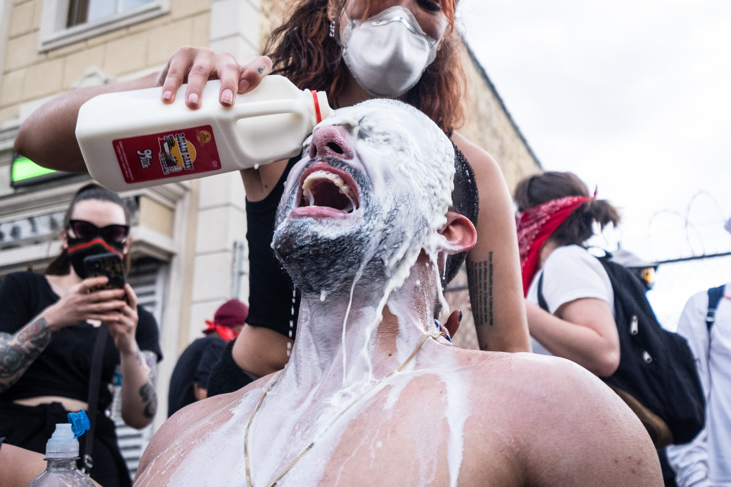  May 30, 2020: New York, NY -   A man has his eyes washed out with milk after being pepper sprayed by police as protesters clash with NYPD officers in Flatbush, Brooklyn after George Floyd was killed while being detained by Minneapolis police on May 