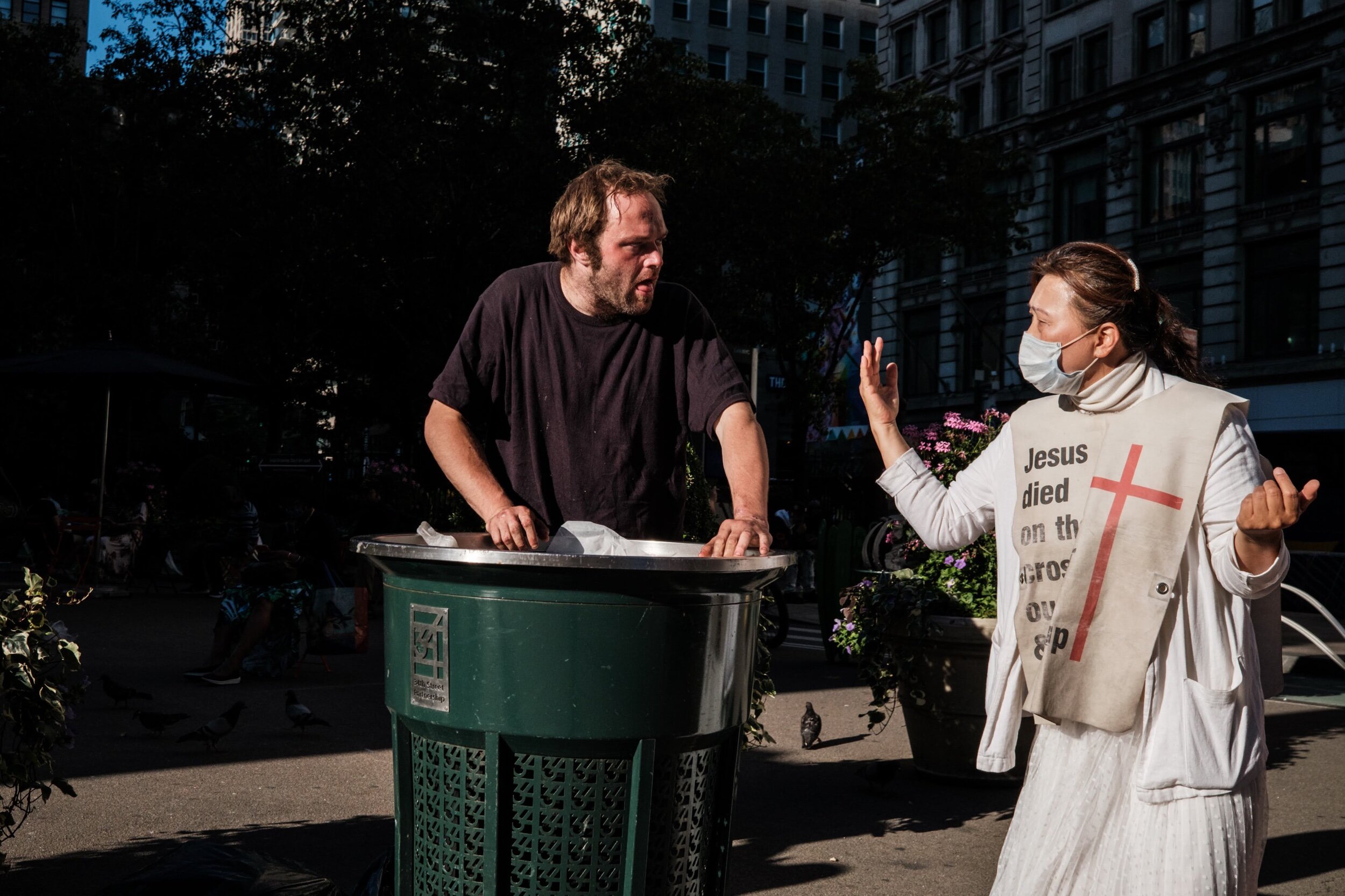  A church worker approaches a man eating out of a garbage can in Midtown Manhattan 