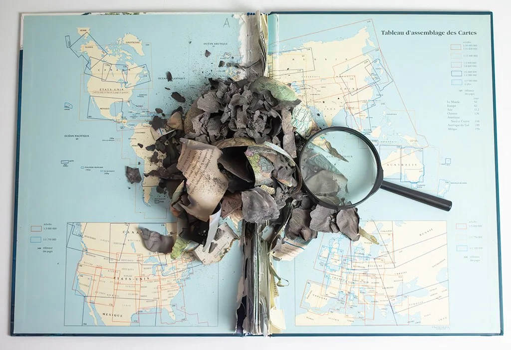 altered book burnt atlas with magnifying glass