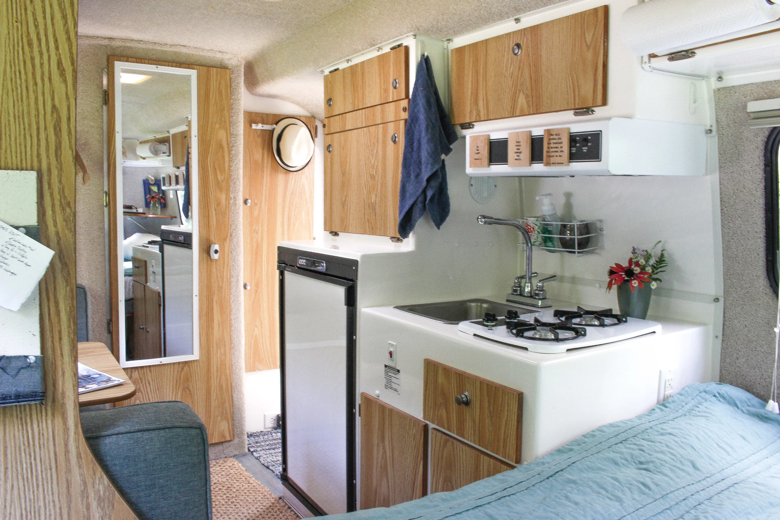 View of the kitchen with the sink, stove top, and refrigerator.