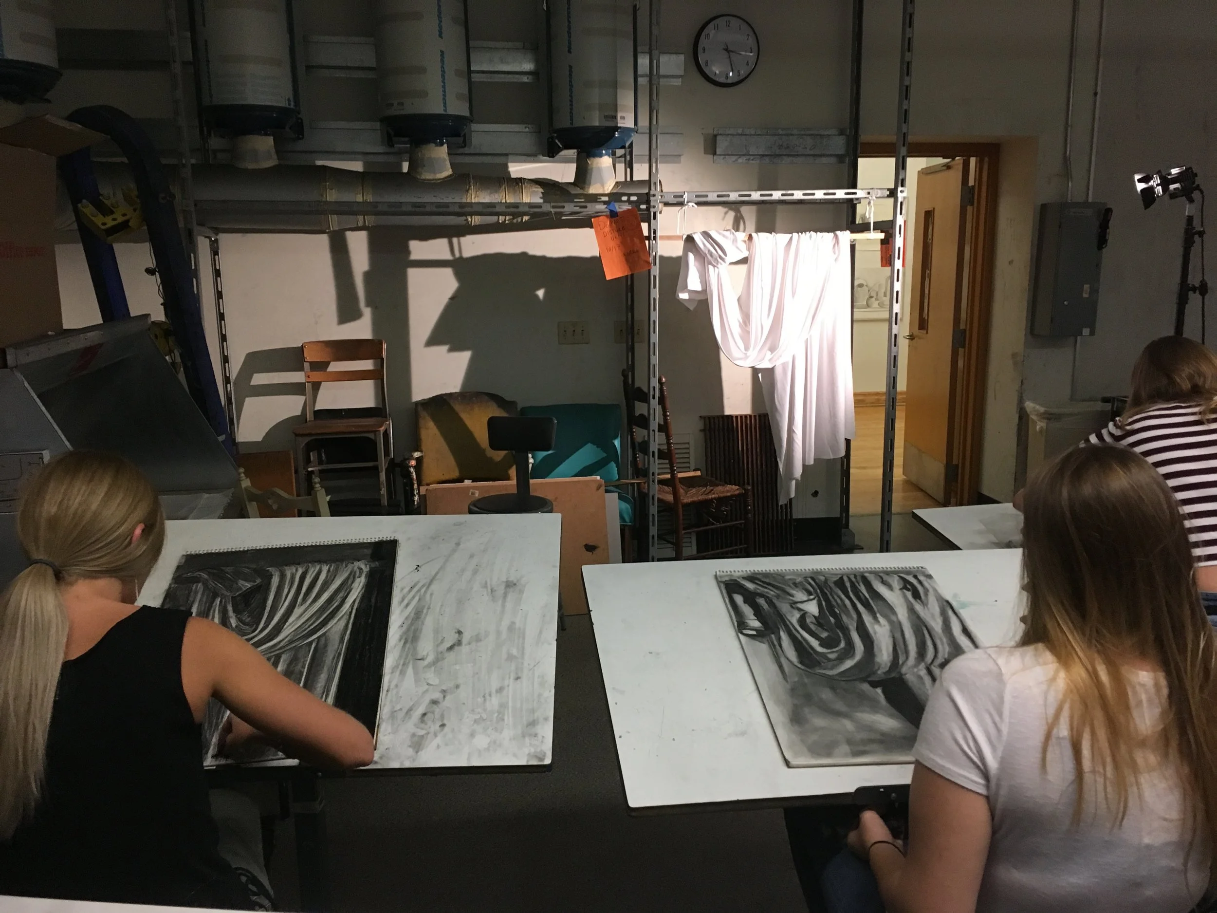 Students draw draped fabric with charcoal using a reductive/subtractive method.