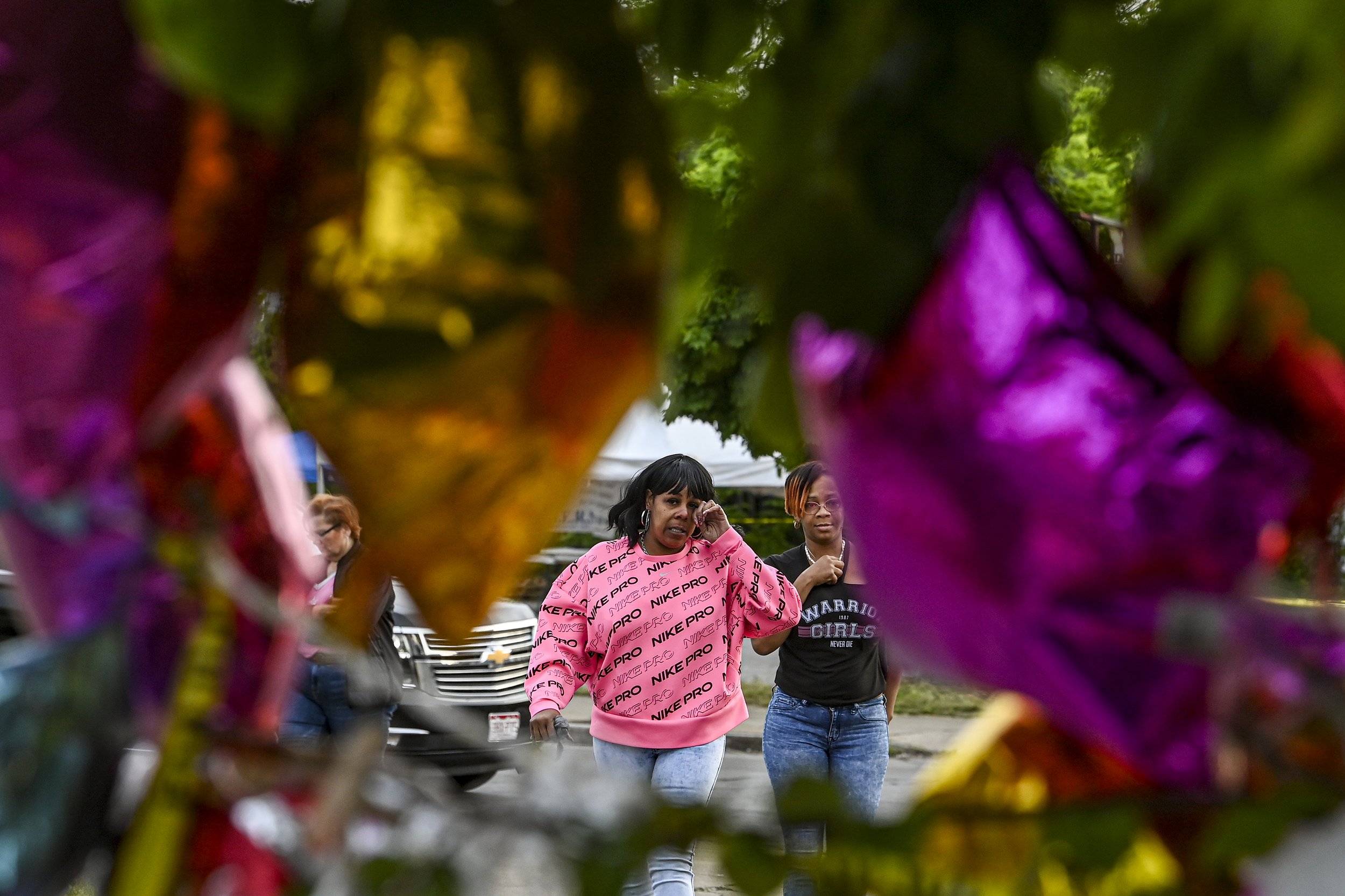  Emotional Buffalo residents are seen through flowers and balloons that make up a memorial outside Tops Friendly Market. 