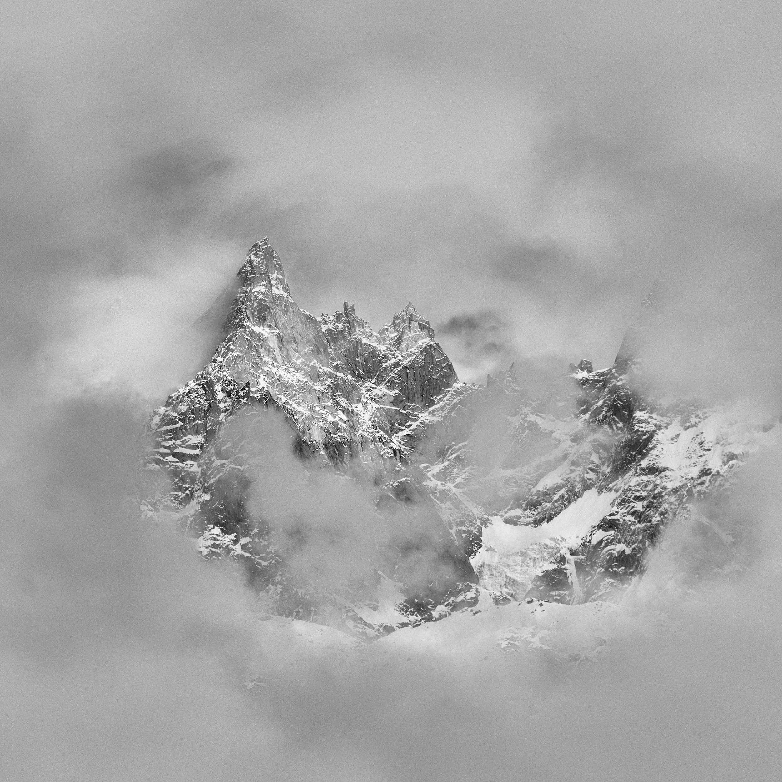 Snow-covered mountain peaks in a foggy, overcast sky.