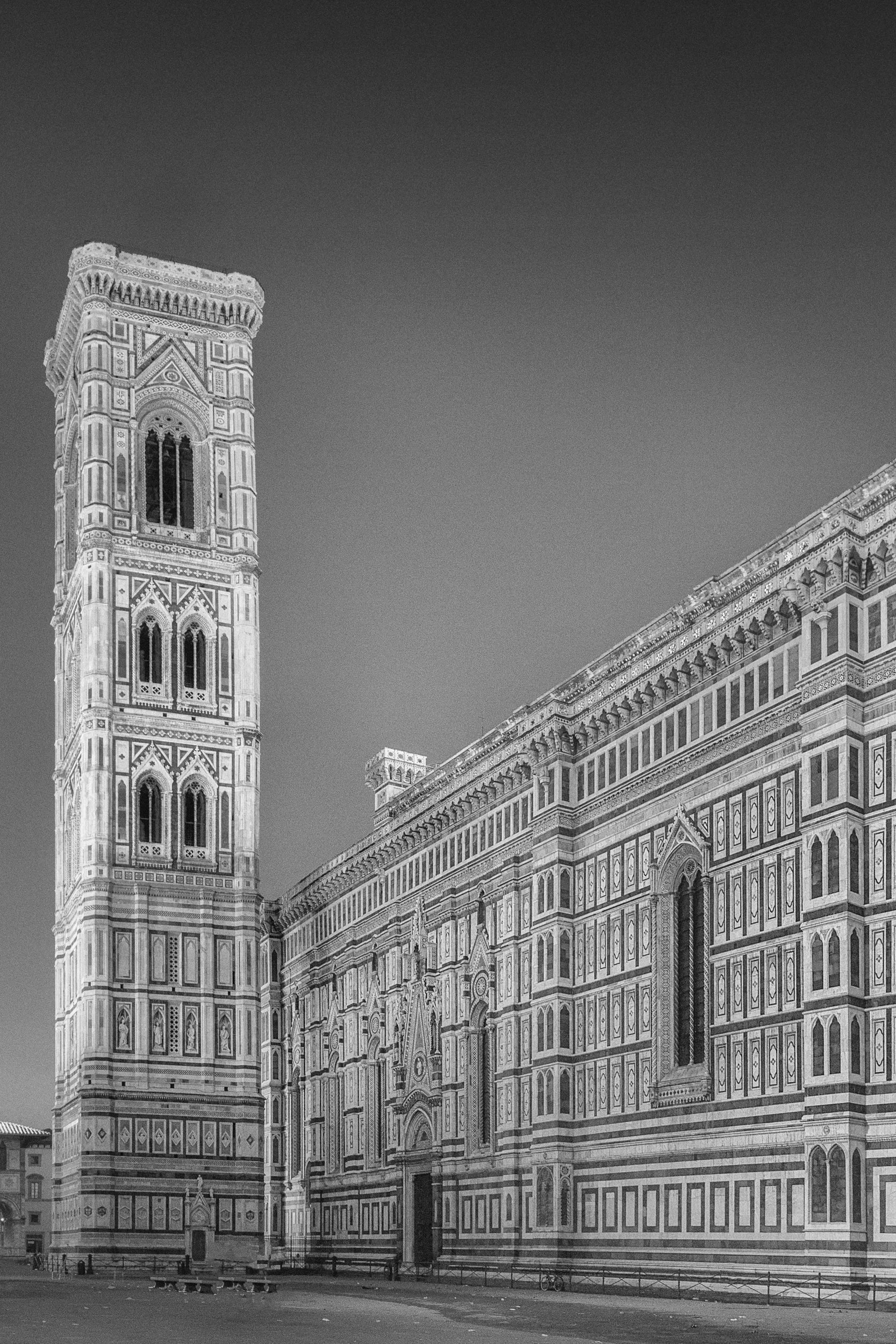 Black and white photo of the Florence Cathedral with its detailed Gothic architecture and Bell Tower in Florence, Italy.