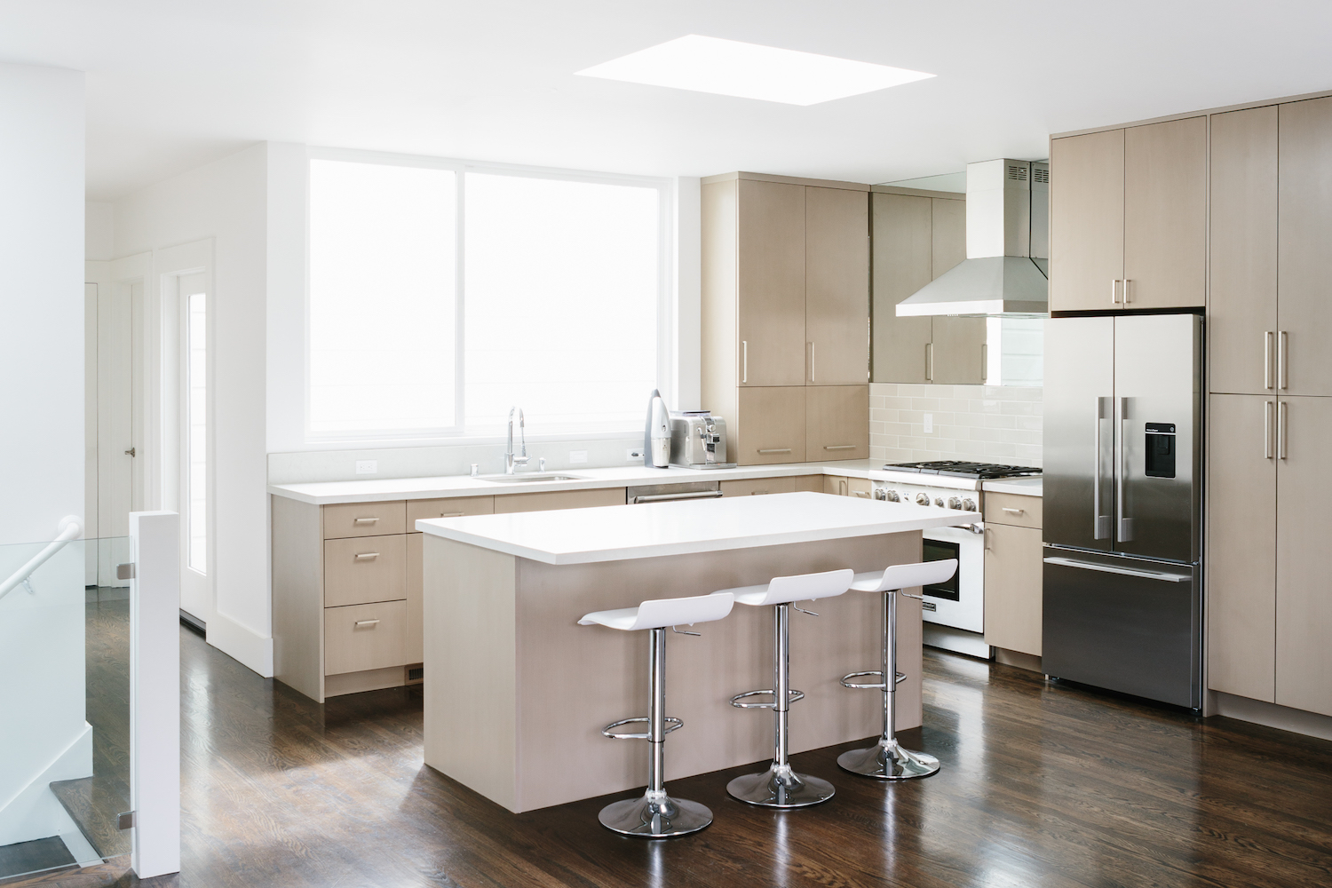 kitchen with light wood cabinets and center island and bar seating and white counters and stainless steel appliances.jpg