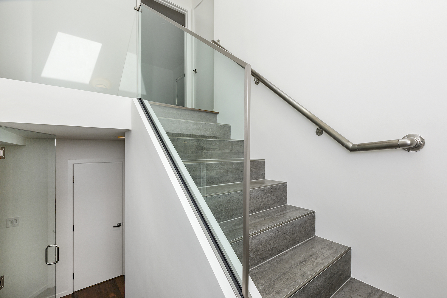 grey tile staircase with glass railing and white walls.jpg