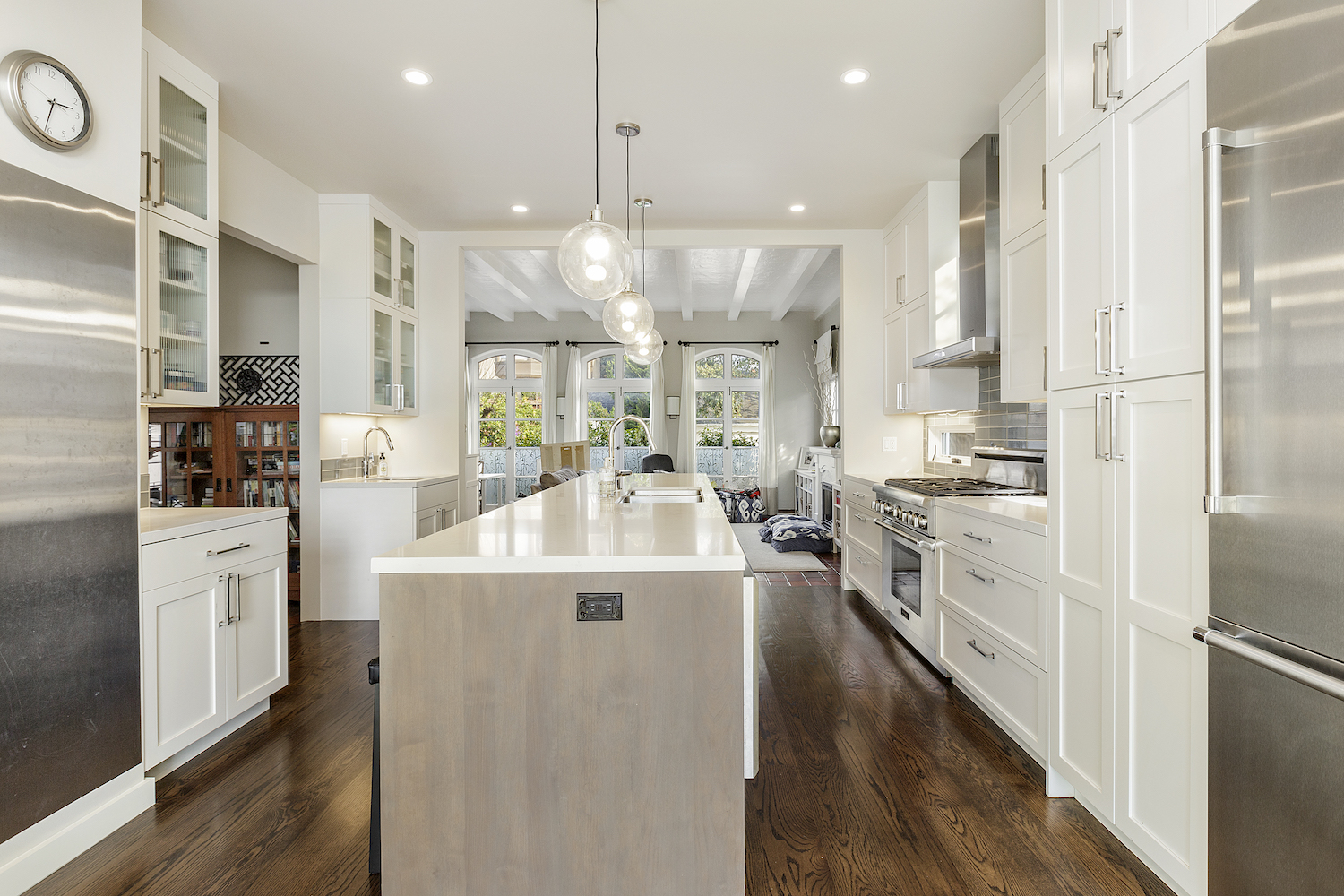 kitchen with white cabinets and stainless steel appliances and large island and wood floors.jpg