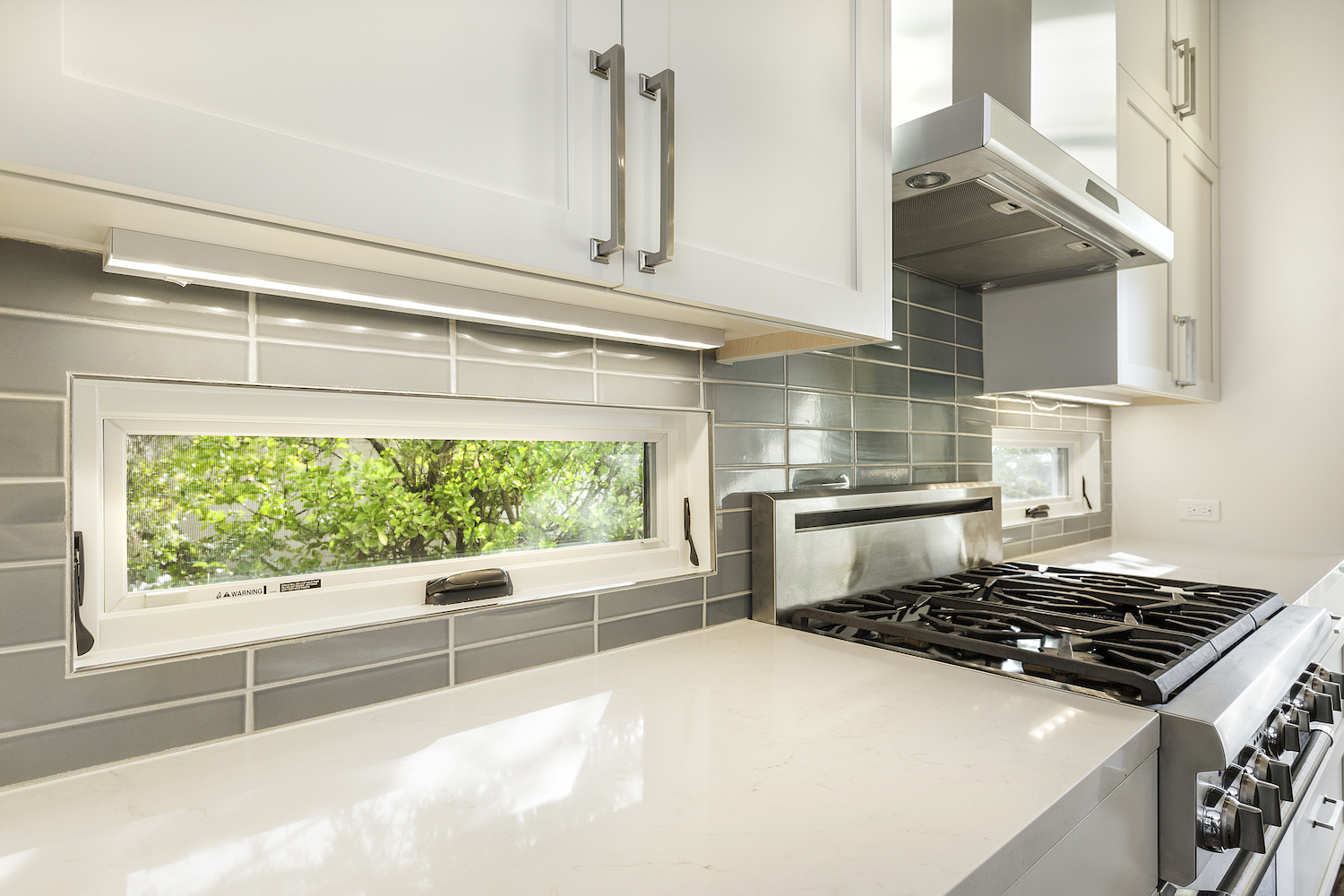 kitchen with white counters and accent windows in grey tile backslash.jpg