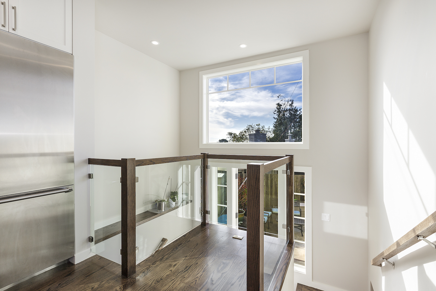stair landing with wood railing and glass panels and large picture window.jpg