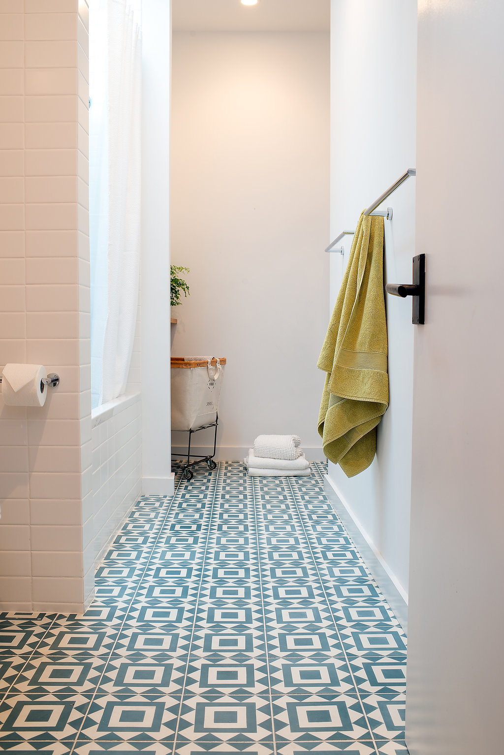 bathroom with white wall tile and blue and white patterned floor tile and chrome hardware.jpg