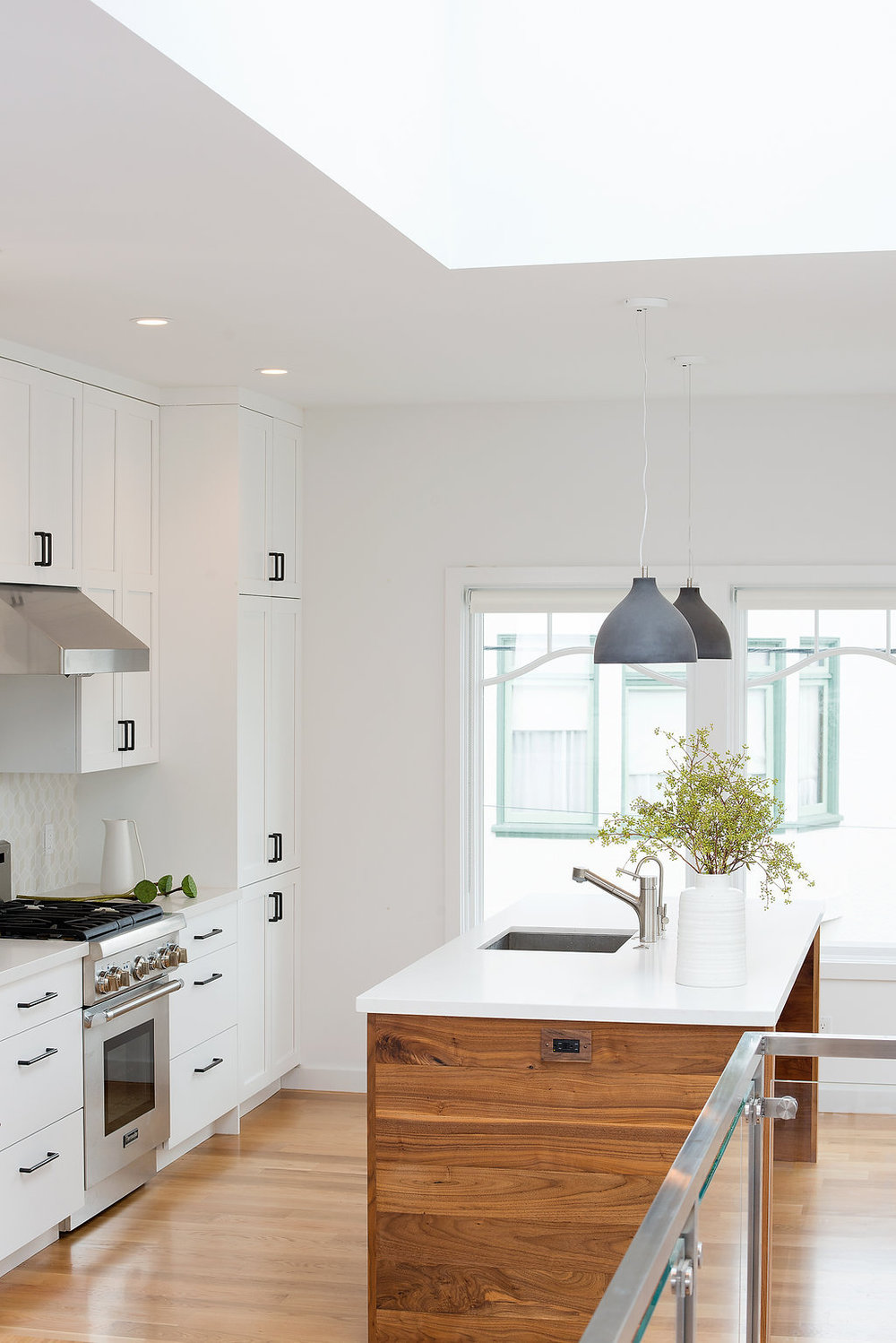 kitchen with white cabinets and wood island and white marble counters and stainless steel appliances and pendant lighting.jpg