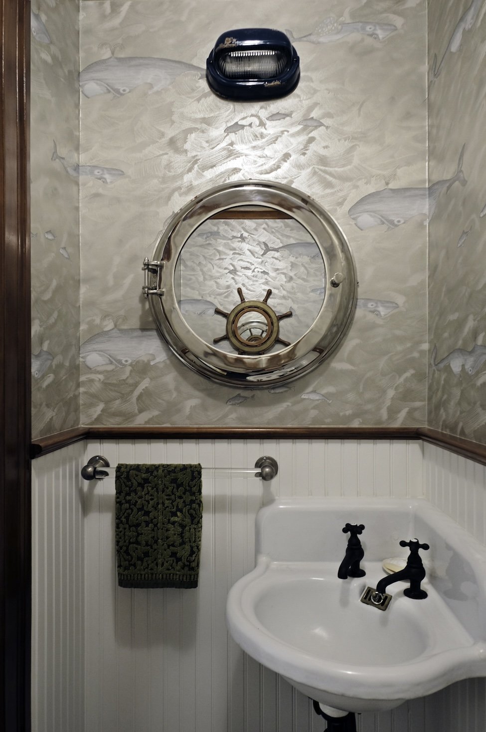 nautical themed powder room with whale wallpaper and corner sink and vintage fixtures.jpg