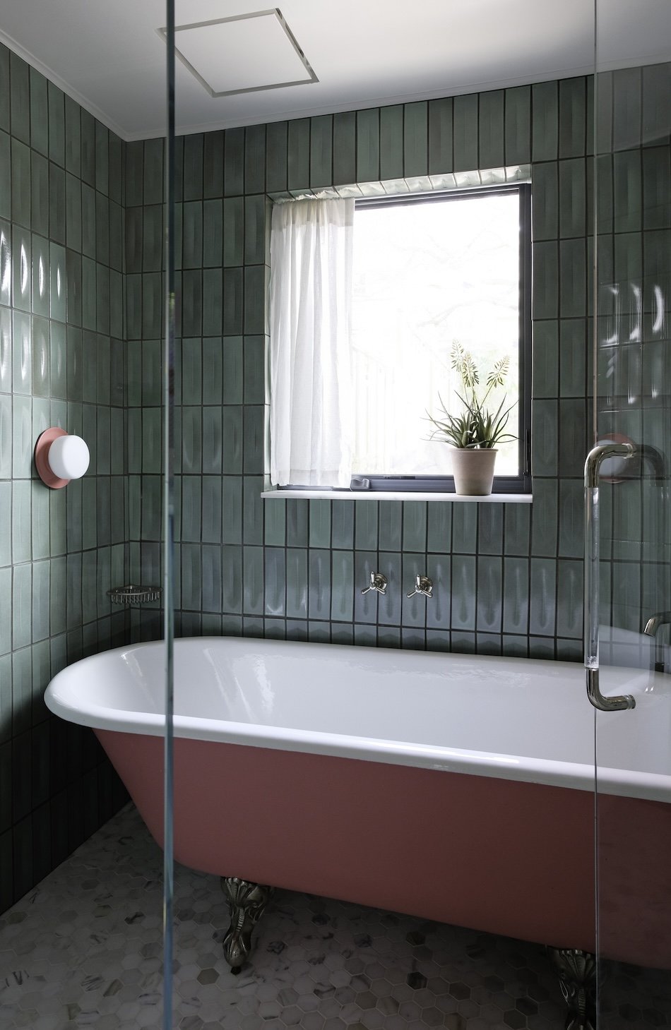 Primary bathroom with pink tub and pink light fixtures and green vertically stacked tile.jpg