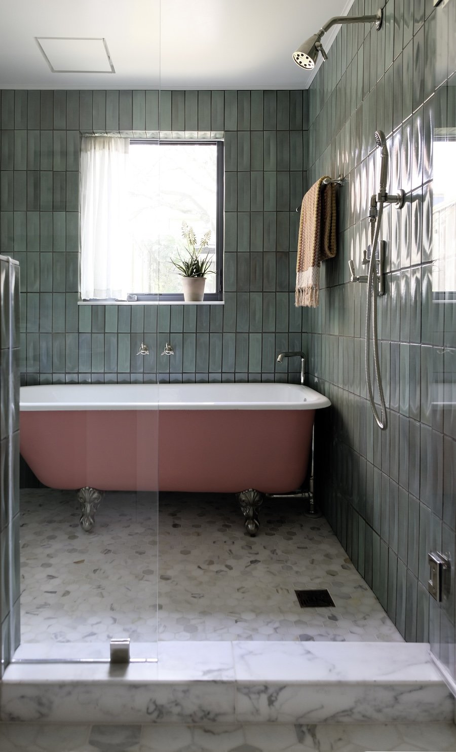 Primary bathroom with polished nickel fixtures and pink tub in shower.jpg