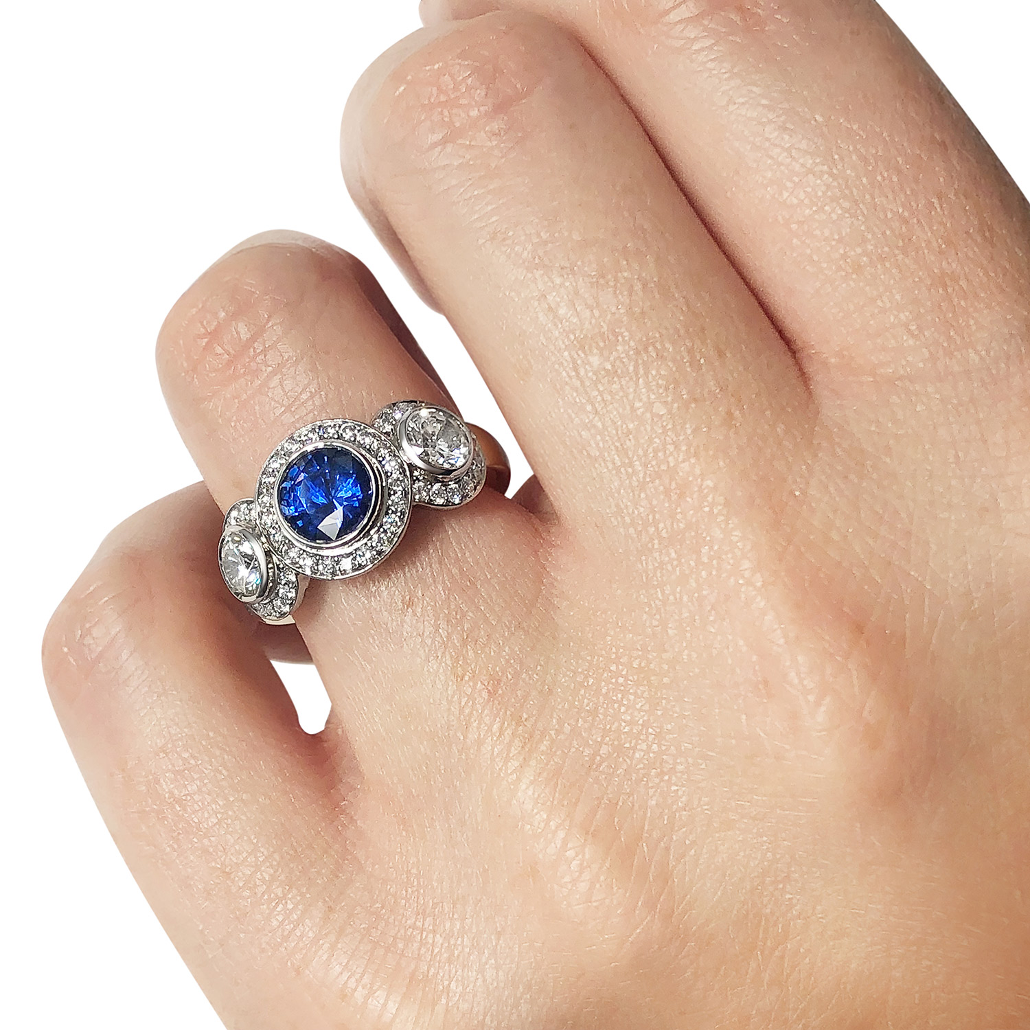 Bespoke sapphire and diamond three-stone halo ring mounted in 18ct white and yellow gold on hand
