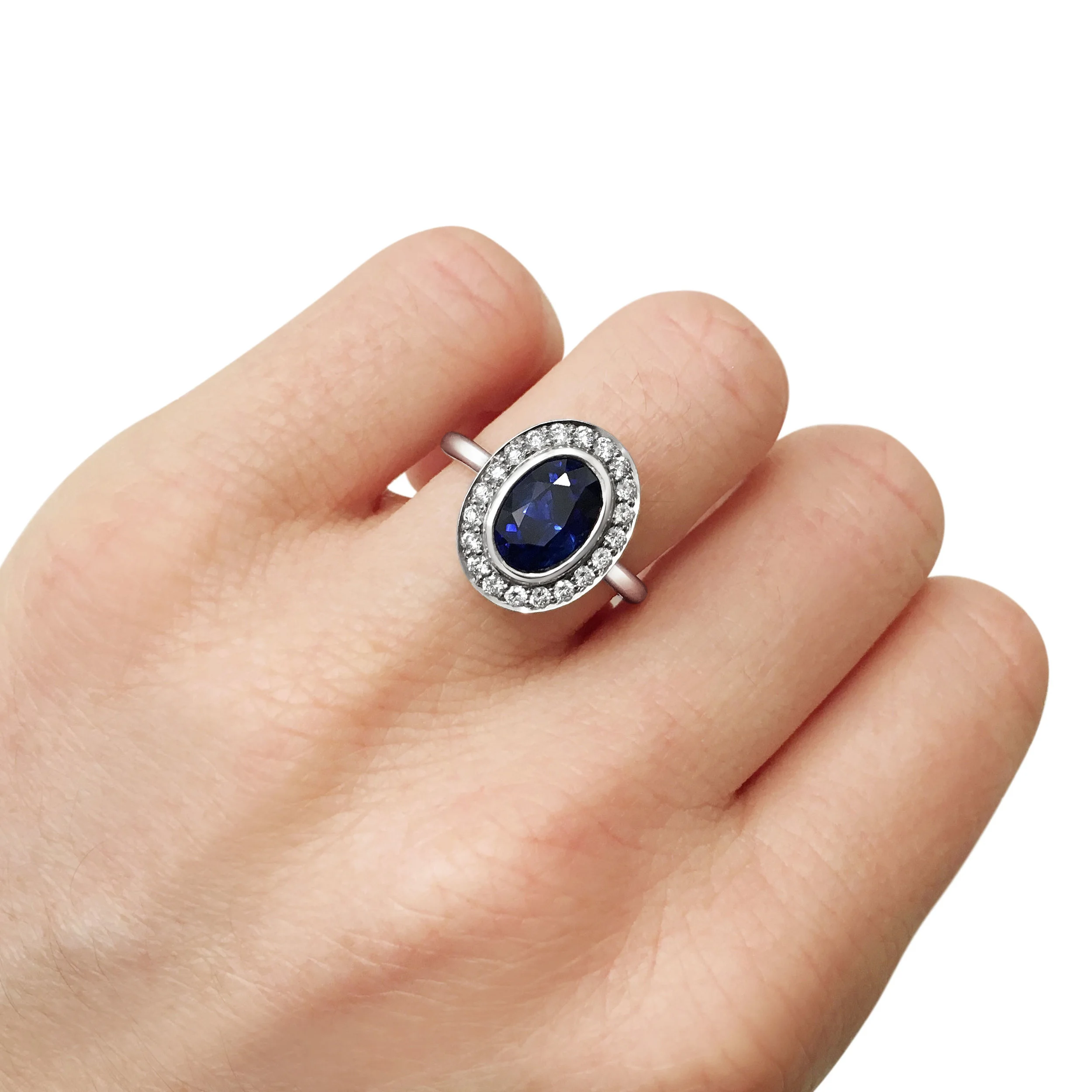 Oval sapphire with diamond halo engagement ring, mounted in platinum.