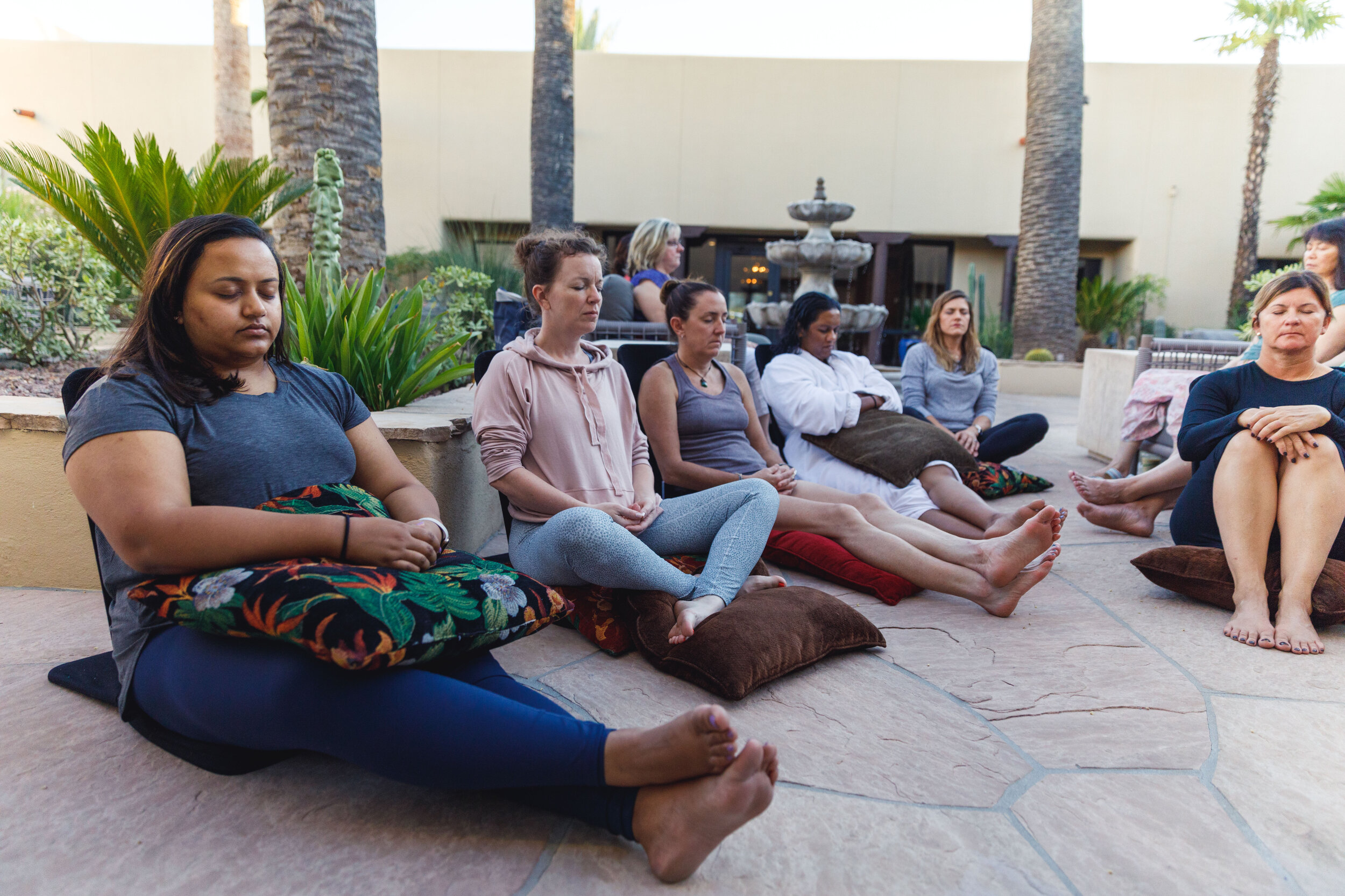 Attendees of the Women in Healthcare Meditation Retreat meditate outside, in a natural setting, sitting comfortably.