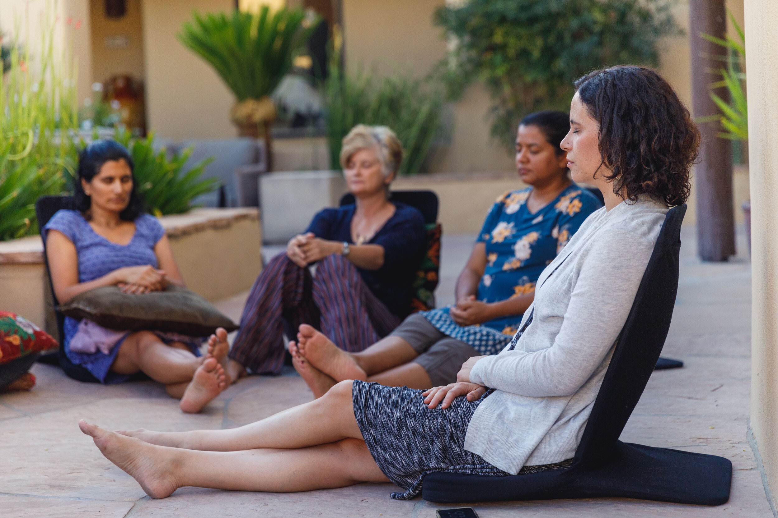 Dr. Jill Wener leads a guided meditation with retreat attendees outside at the retreat center, seated in comfortable floor chairs. 