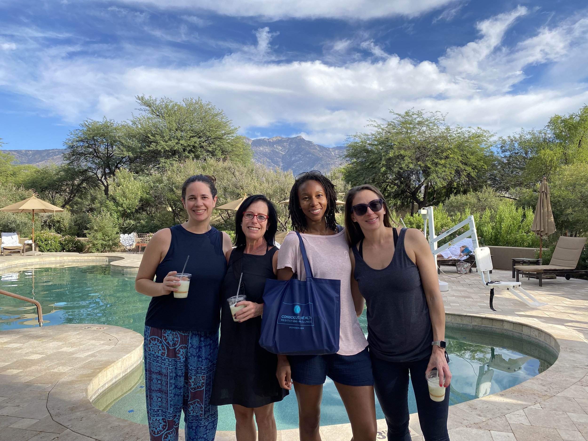 Dr. Jill Wener poses with retreat attendees who are enjoying refreshing drinks, standing by the pool at the retreat center.