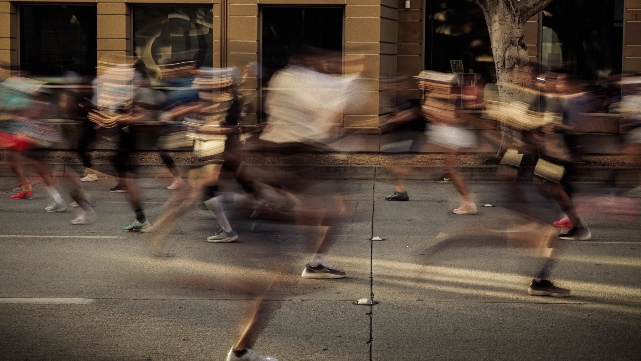 A group of runners participating in a race, captured with motion blur on a city street.