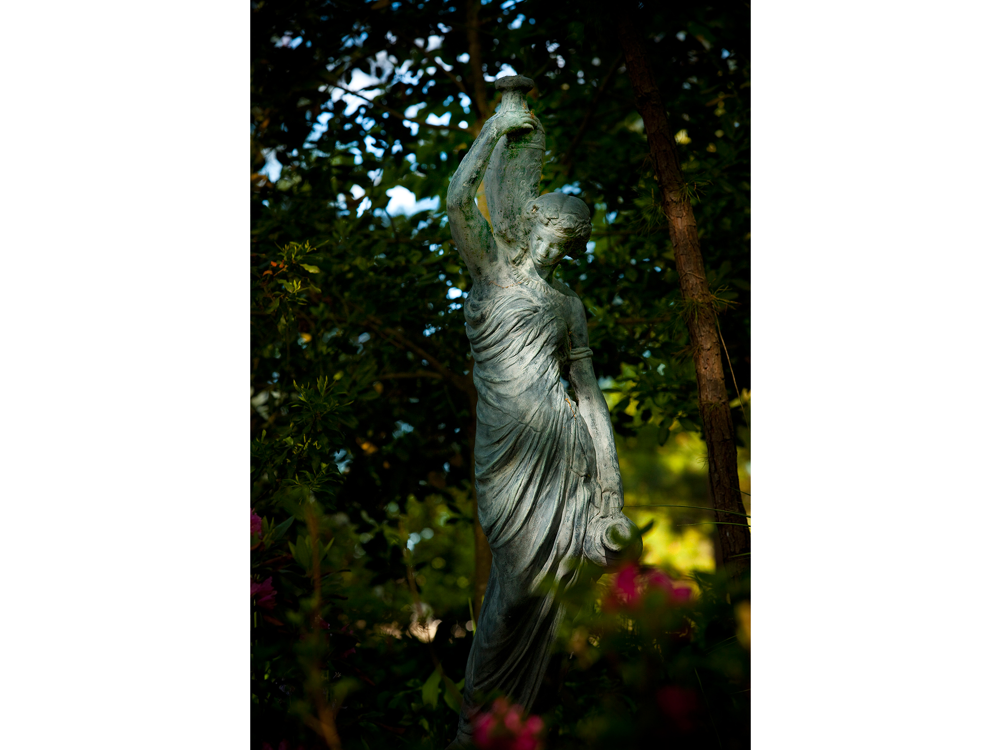 Statue of woman with flowers in the forest photograph