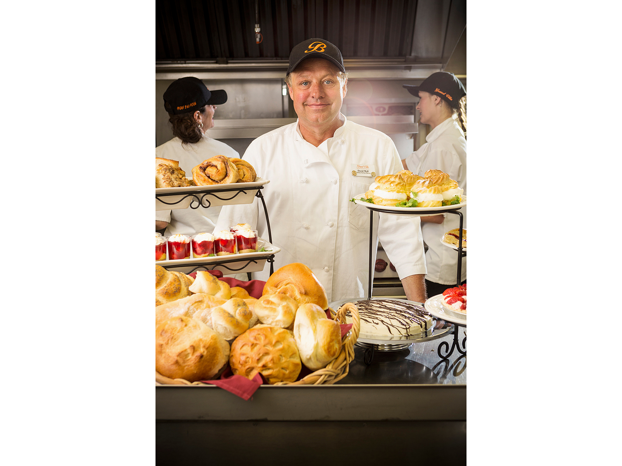 Pastry chef in kitchen with pastries on display
