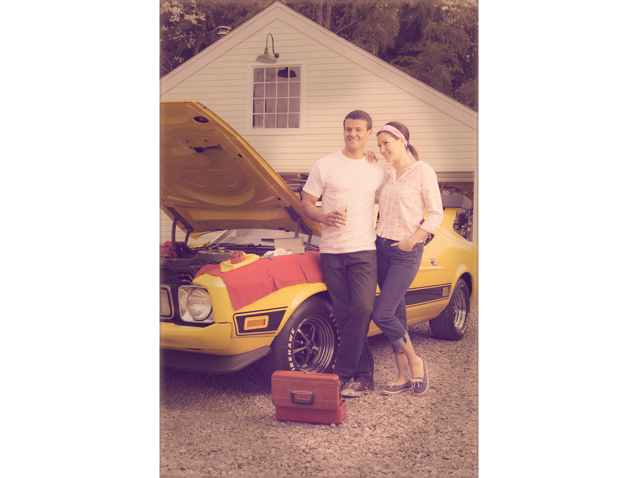 Retro photo of young couple working on yellow Ford Mustang