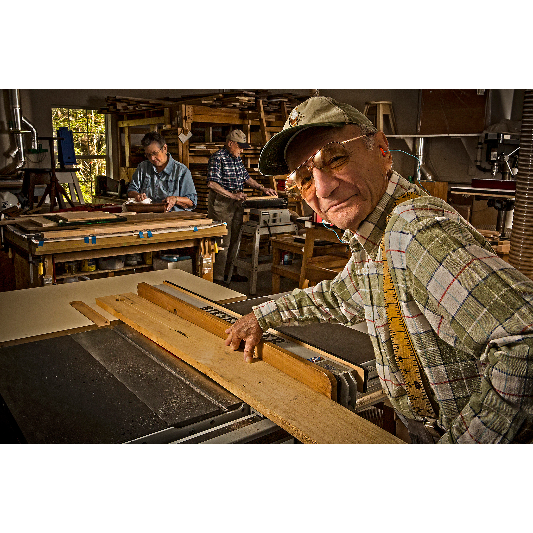 Senior man in woodworking shop sawing wood