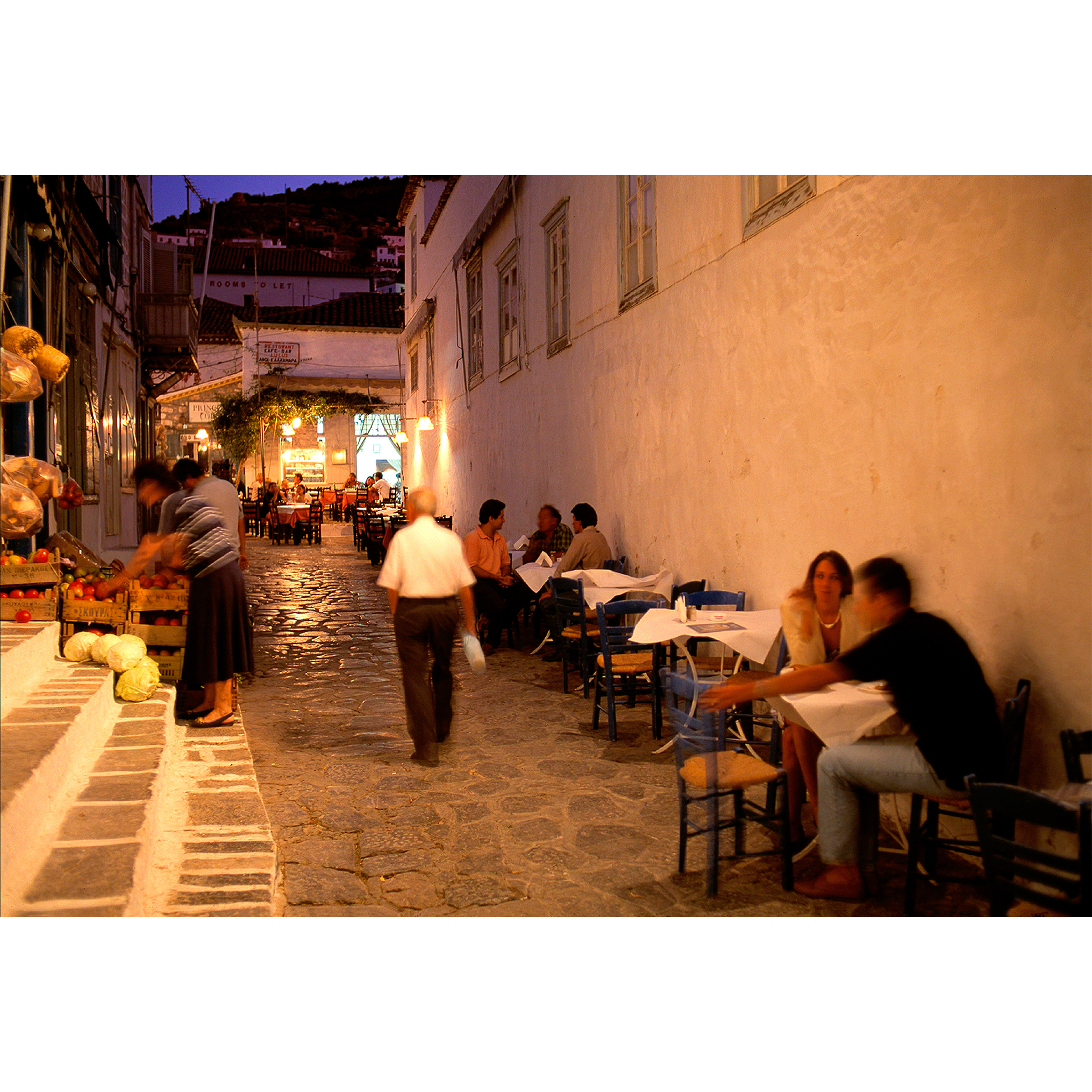 Photo of outdoor Greek restaurant at night with people eating