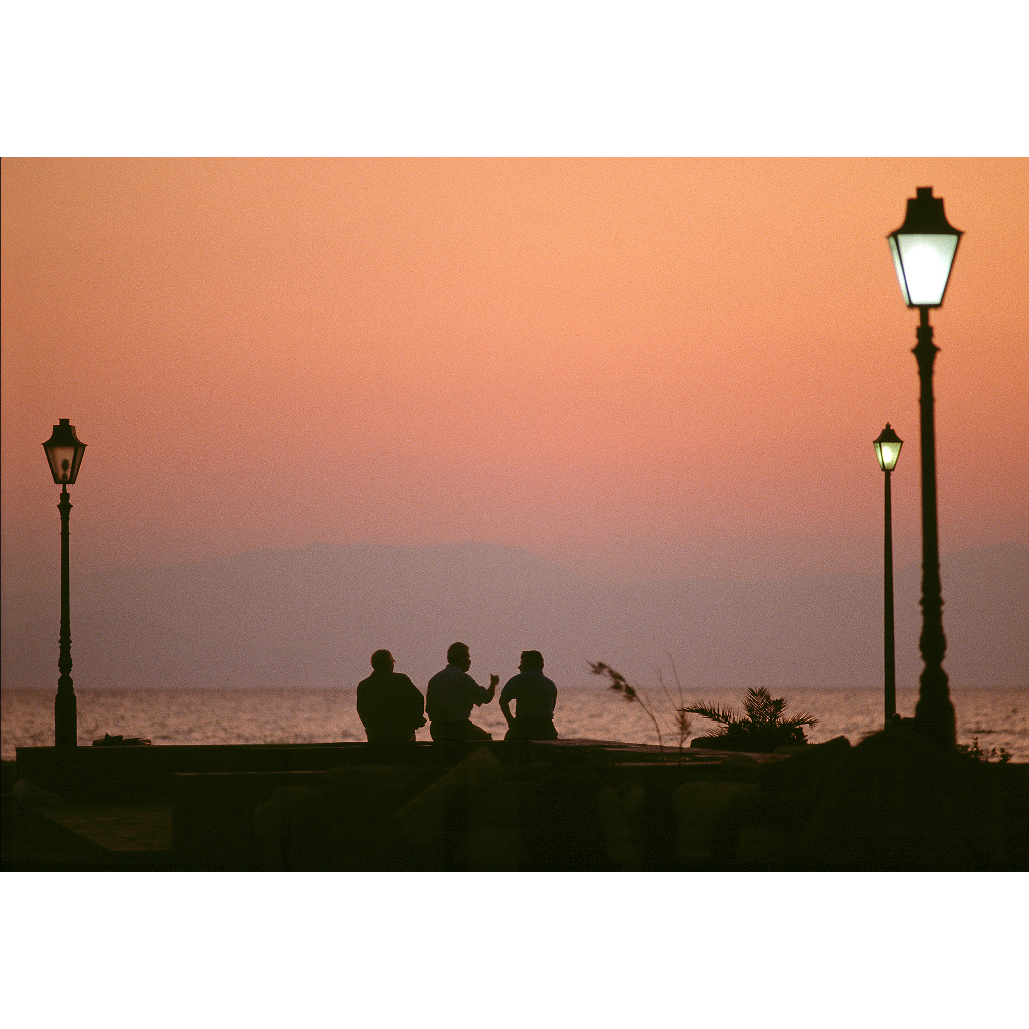 Greek men at sunset overlooking water photograph