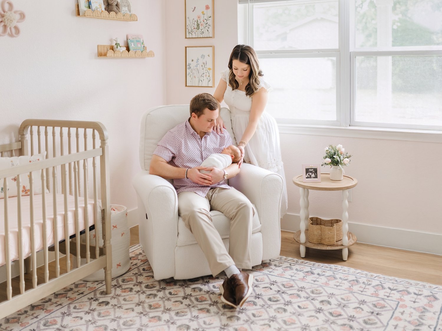 mom and dad holding baby girl in nursery for newborn photoshoot