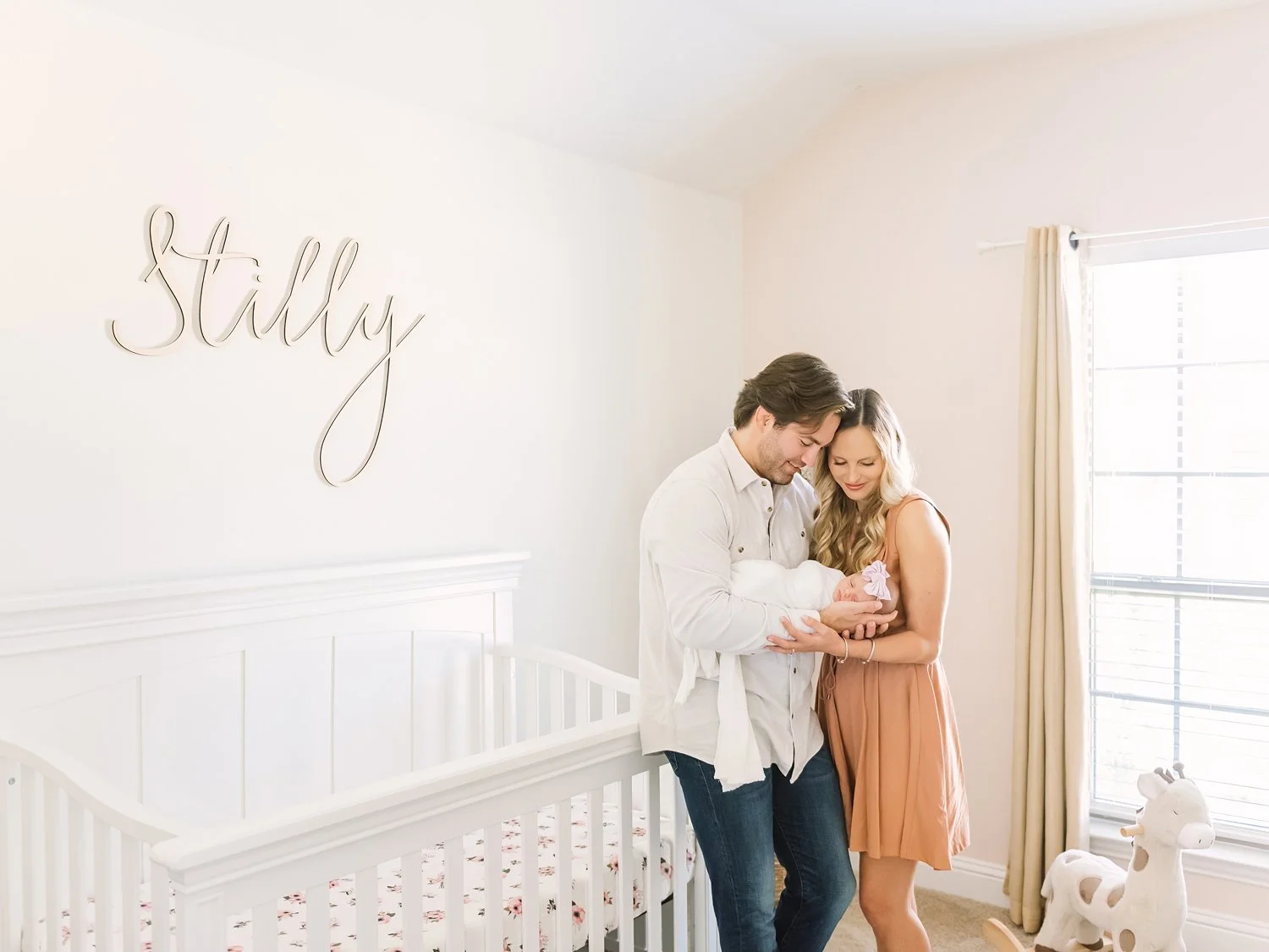 couple holding baby girl at home in nursery