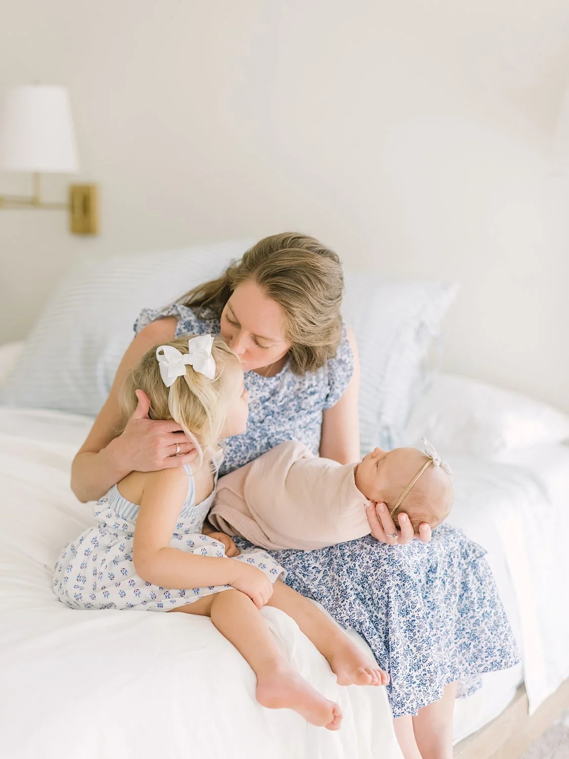 mom with newborn baby and sibling big sister share a sweet moment