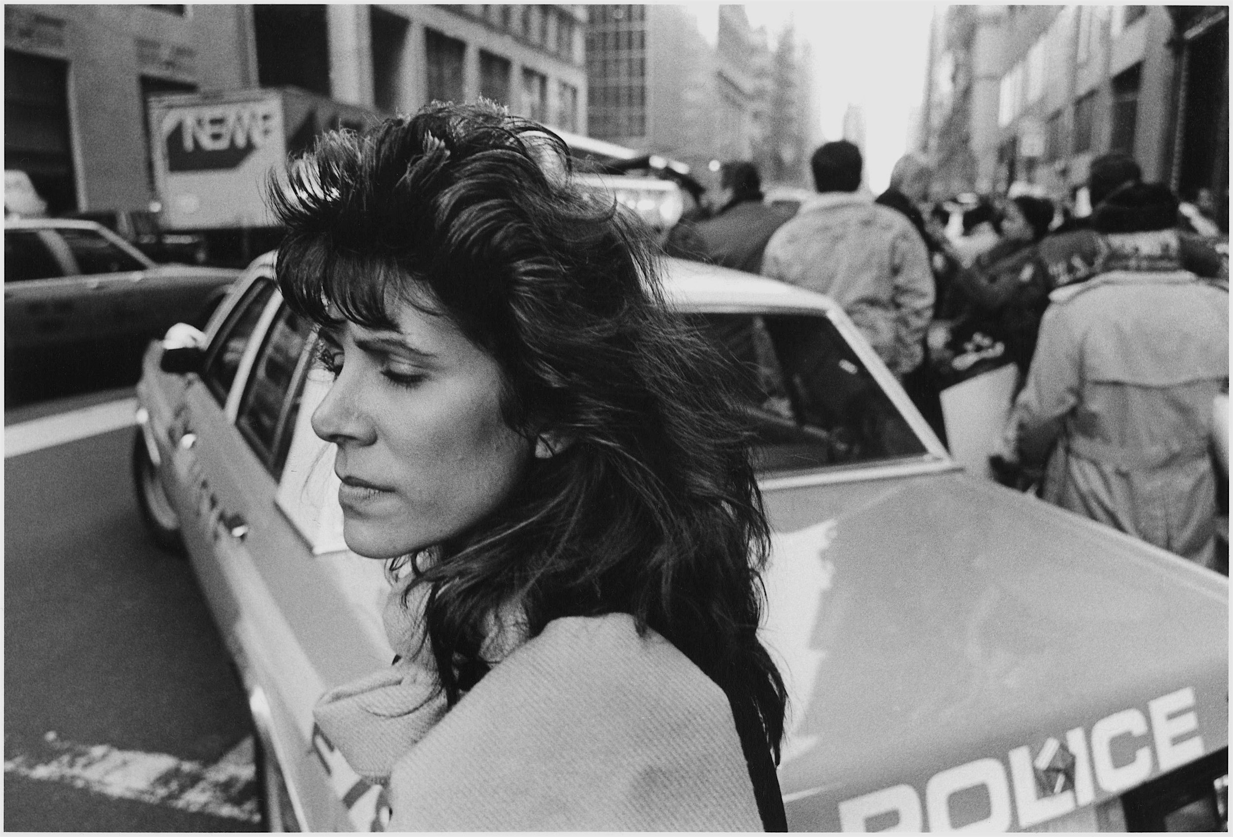 woman's eyes closed behind cop car, nyc, early 1980’s