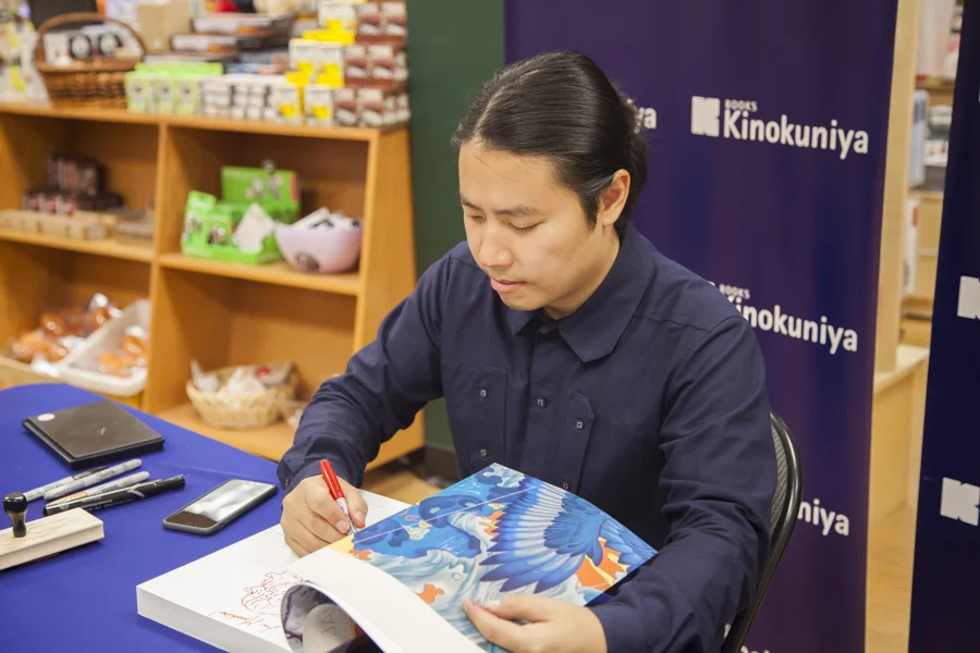 James Jean signs a book.