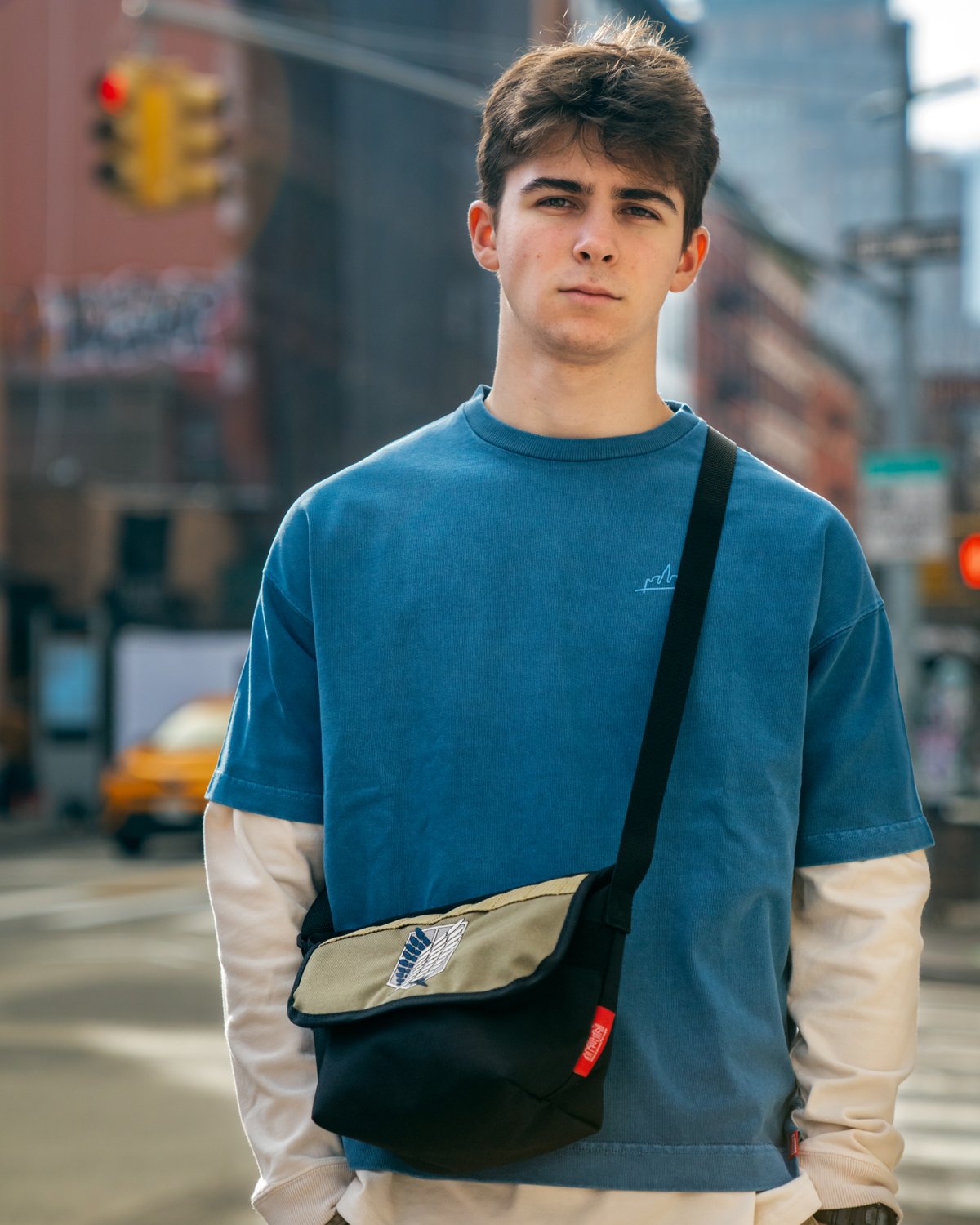  man in blue shirt with Manhattan Portage x Attack on Titan bag 