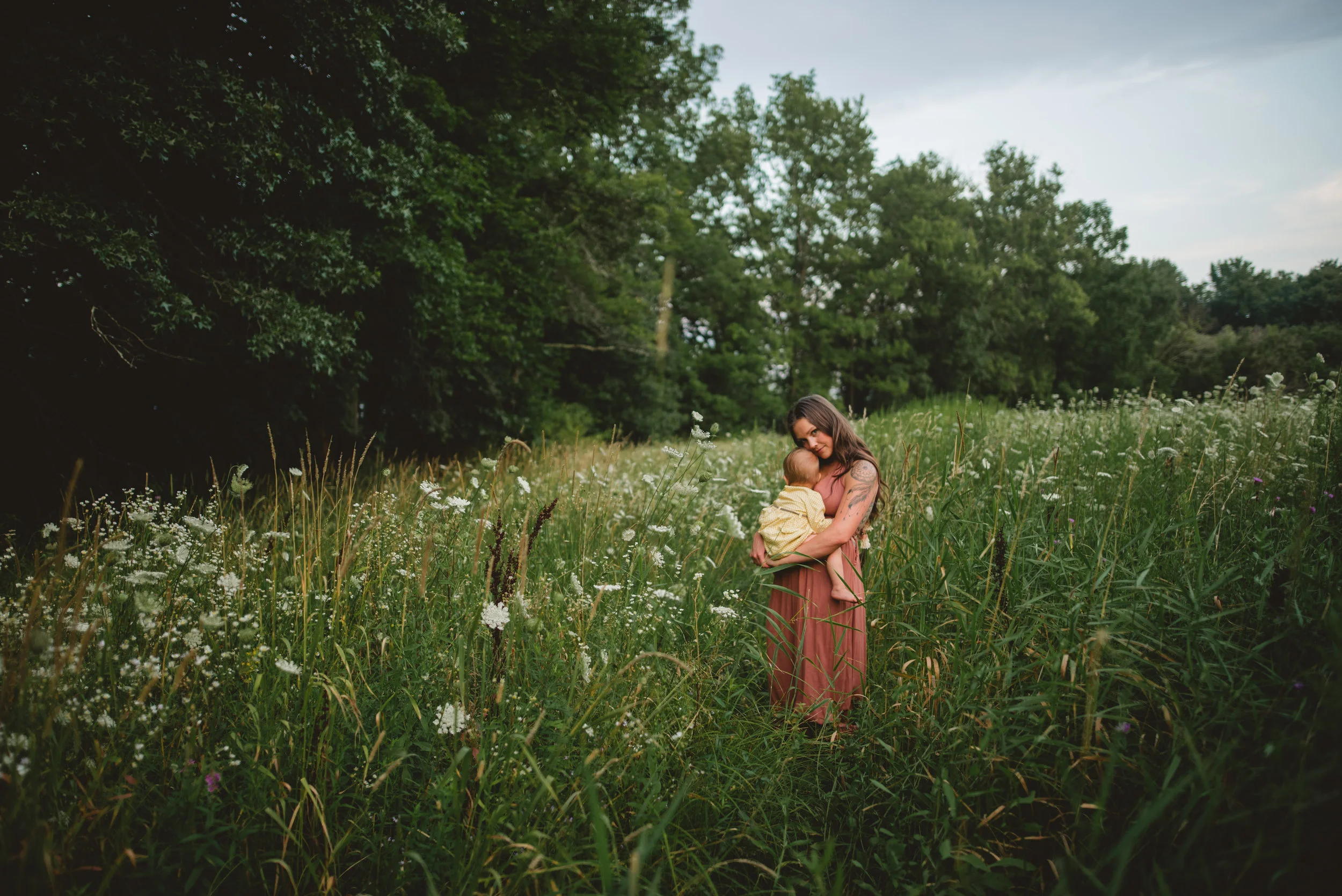 Mommy nursing baby in field of queen annes lace flowers