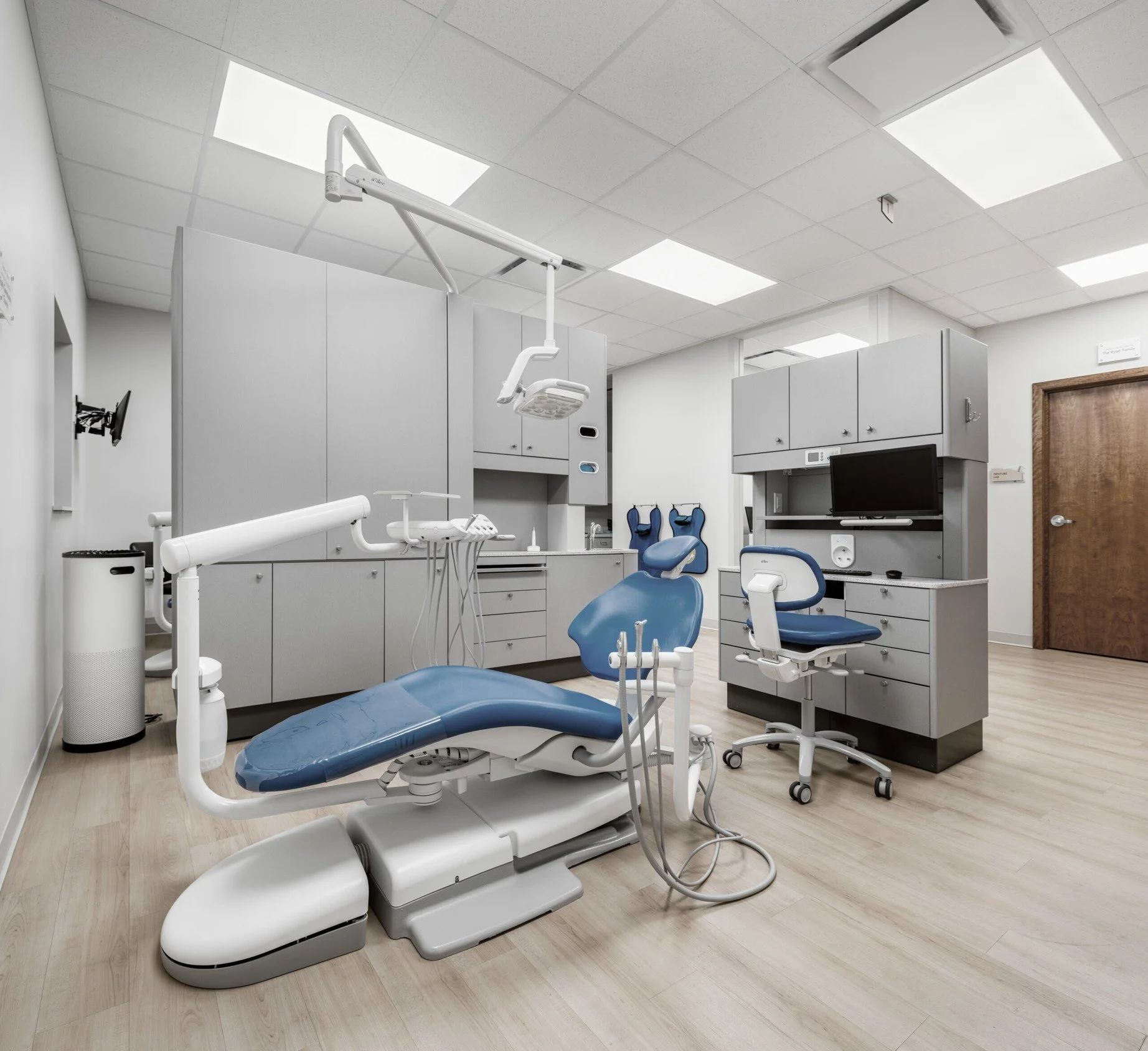 empty dental operatory with gray cabinets and white and blue dental chair unit