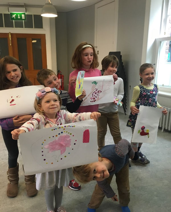 Photo by Rachael King, showing the children displaying their artwork based on the story of The Grumpy Gecko, where a gecko learns that the natural world is a series of connections.