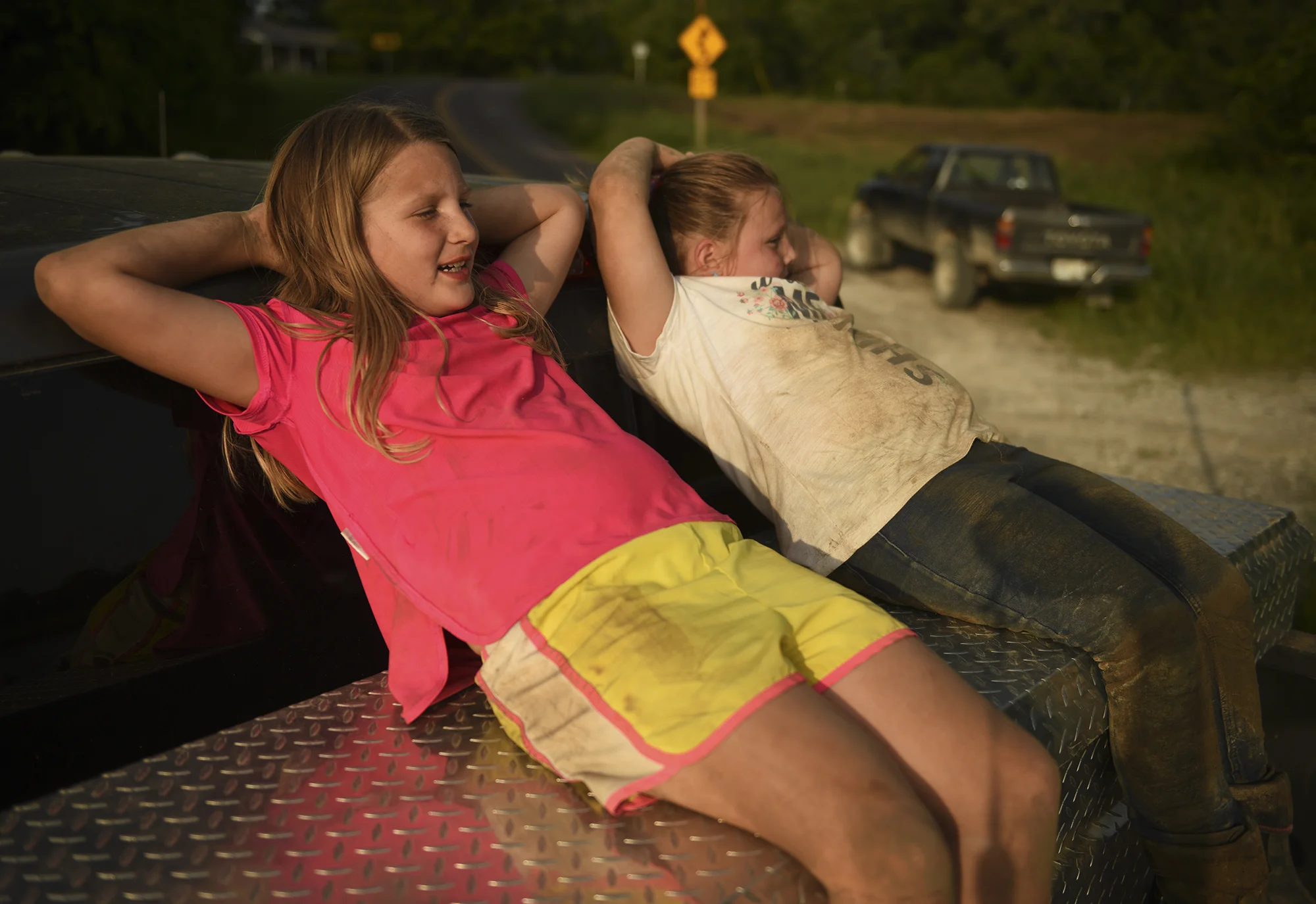 Mia Heyen, 8, and Rylie Skouby, 6, rest on top of a truck after playing in the dirt on Tuesday, May 22, 2019, in Wilton, Mo. Locals and volunteers had been sandbagging all day while most of the children were playing with each other.