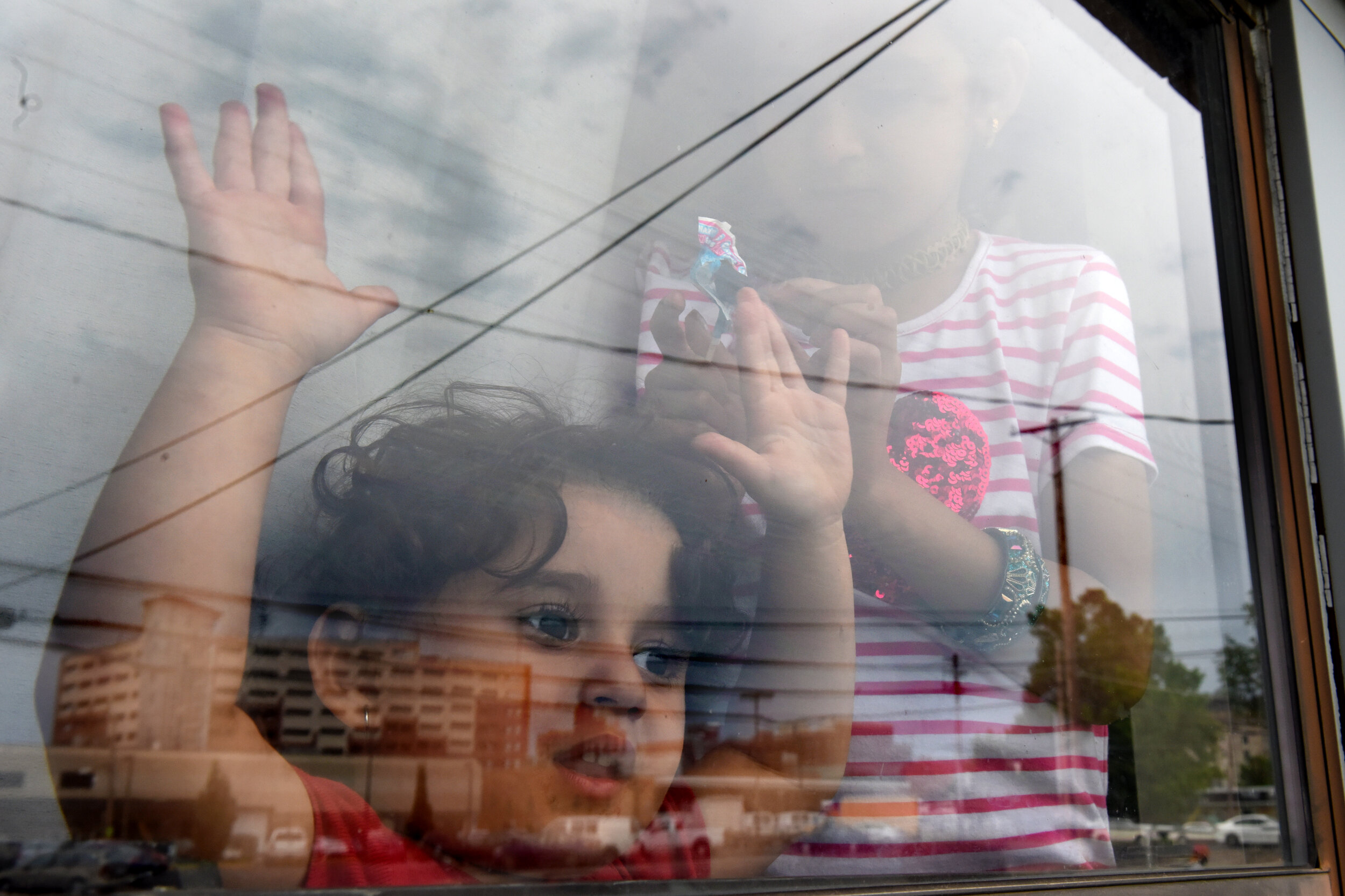  Asinat, 2, looks out the family’s living room window towards downtown Columbia, Mo. The youngest children constantly want to play outside, but their older siblings fear for their safety and their mother is usually taking care of the other kids, prep