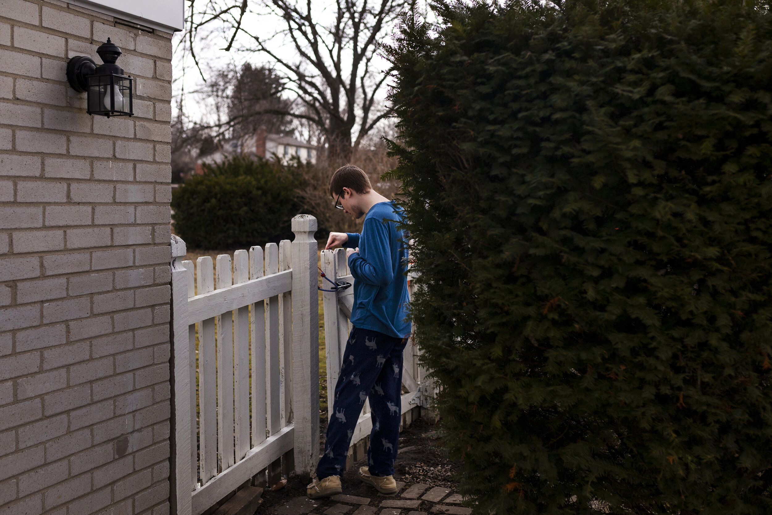  Andrew Carleton, 19, picks at paints chips on a wooden fence in his backyard on Wednesday, March 10, 2021, in Troy. Andrew, who's is diagnosed with autism, has moments of intense focus, according to his father, Bob Carleton.  