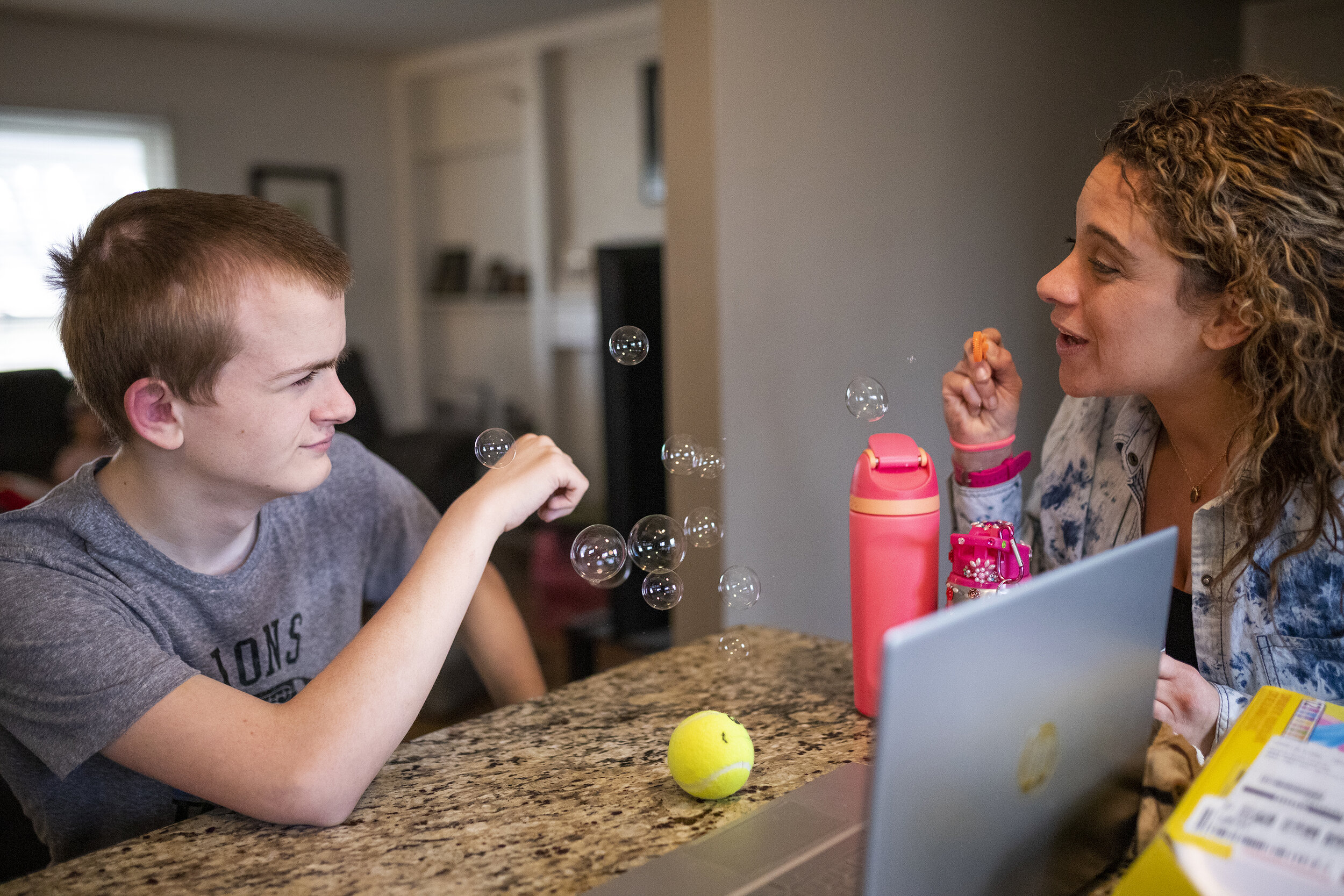  Danielle Vernon-Carleton blows bubbles at her step-son Jackson Carleton, 16, to ease his emotions while he attends a virtual physical therapy class on Wednesday, March 10, 2021, in Troy. Danielle had to resign from her job as a teacher after being d