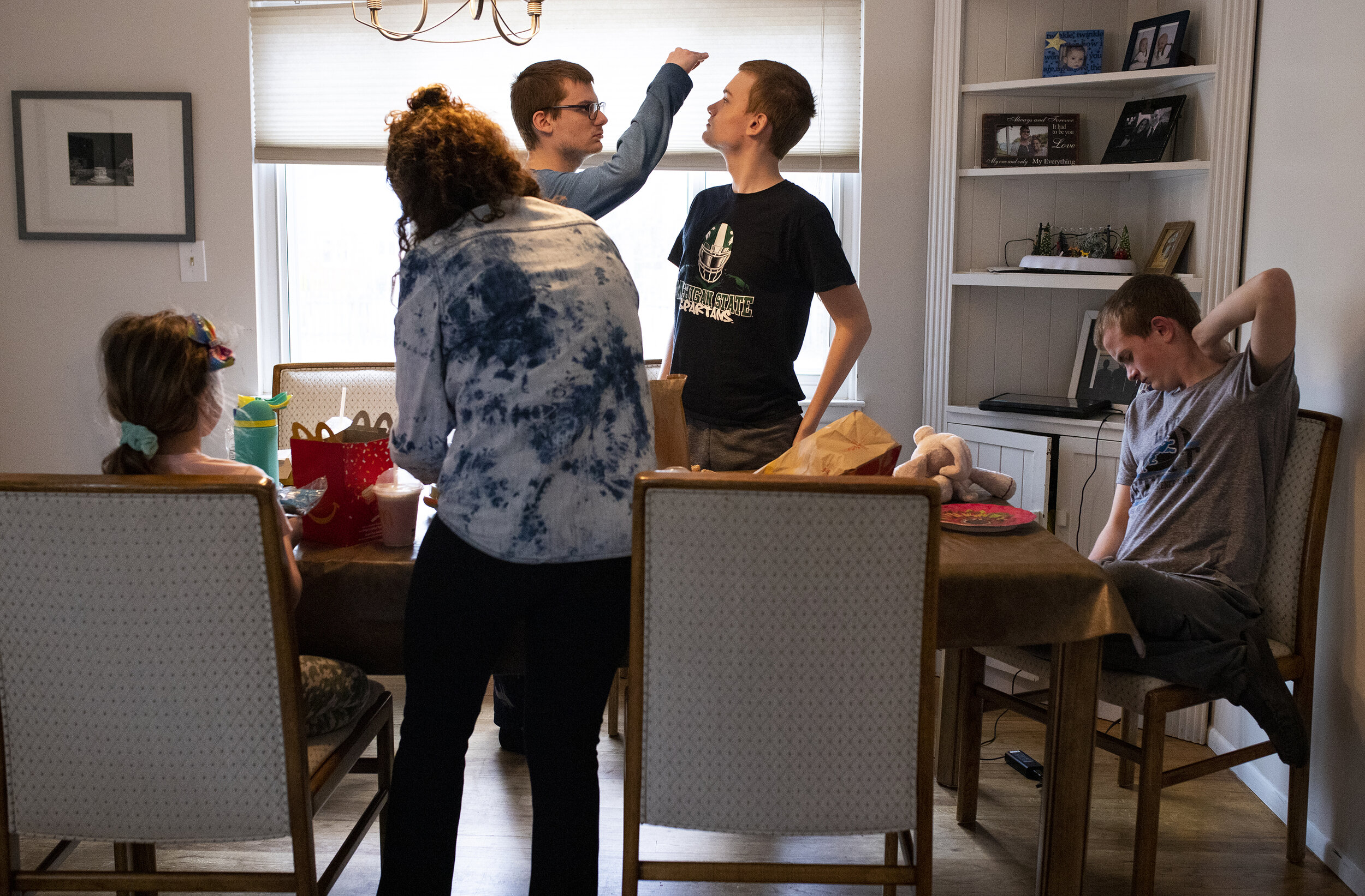  Andrew Carleton, middle left, measures his height against his younger brother Connor's, middle right, on Andrew's nineteenth birthday on Wednesday, March 10, 2021, in Troy. Andrew, Connor and their brother, Jackson, right, all require special needs.