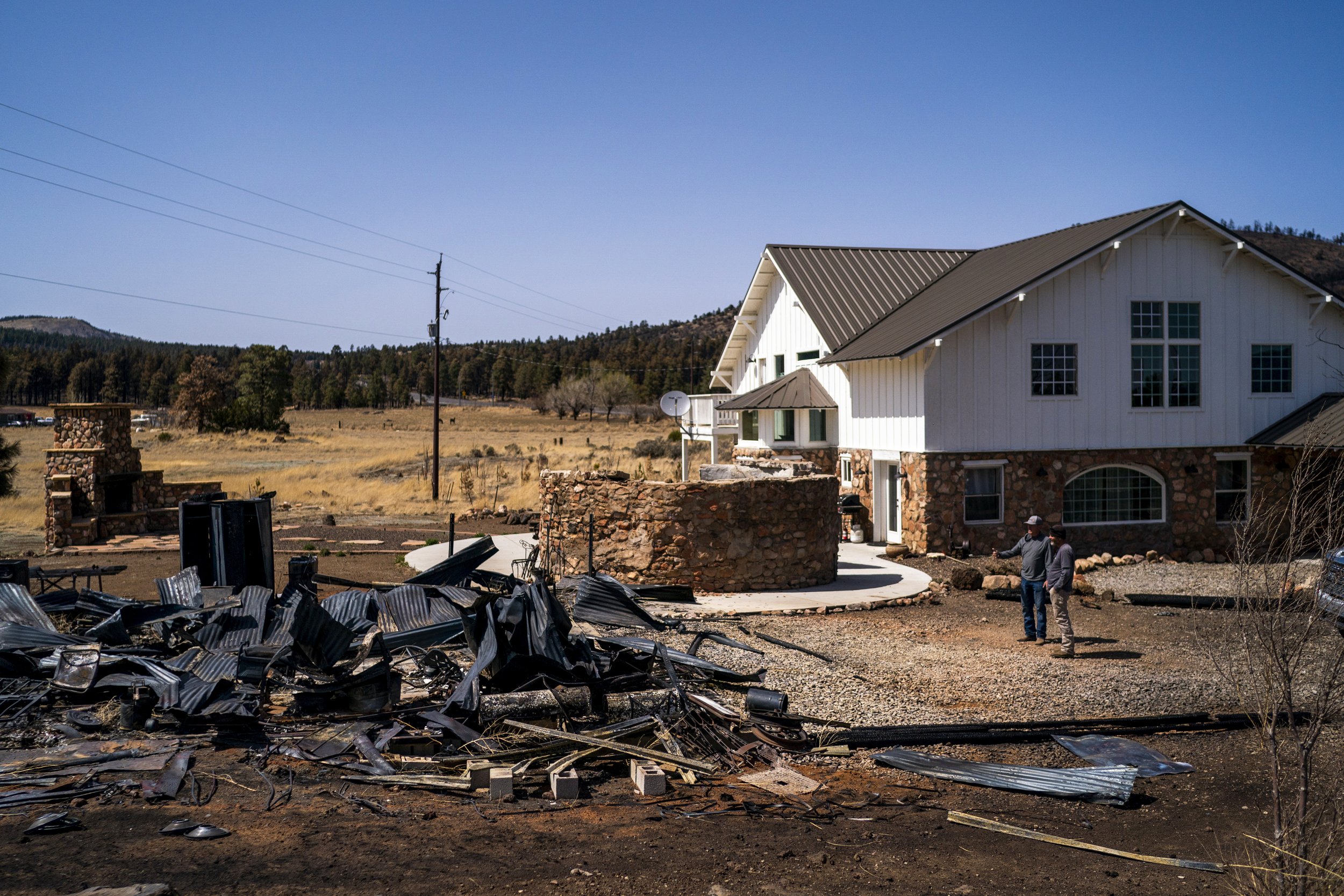  Travis Hopkins and his neighbor Art Collum look over a historic barn that was burned down at his home as residents were allowed to return to their homes after a fire burned through parts of northeast Flagstaff near the Highway 89 on April 24, 2022, 